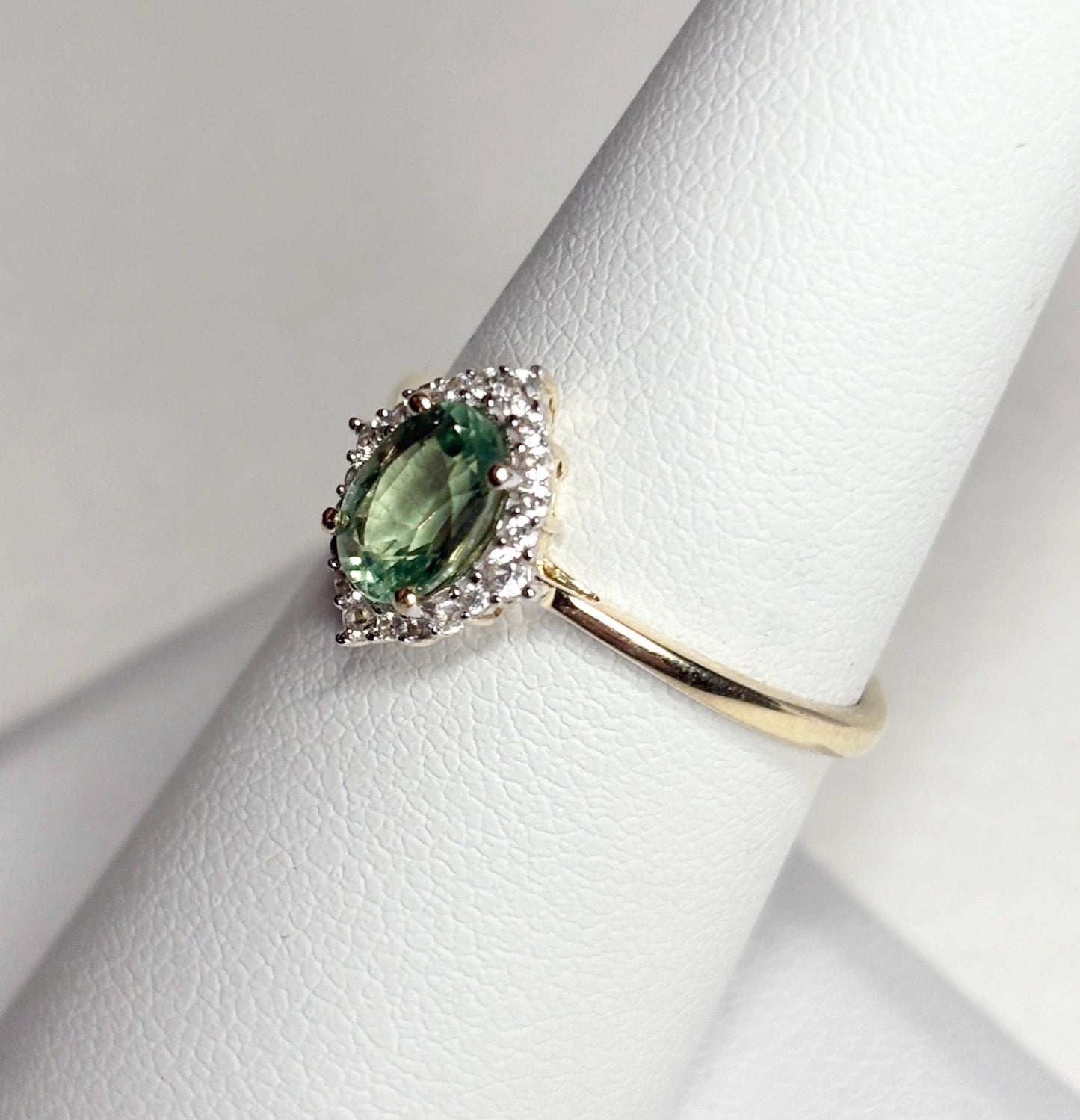 A 9k gold ring with a mint green kyanite center stone and a zircon halo.