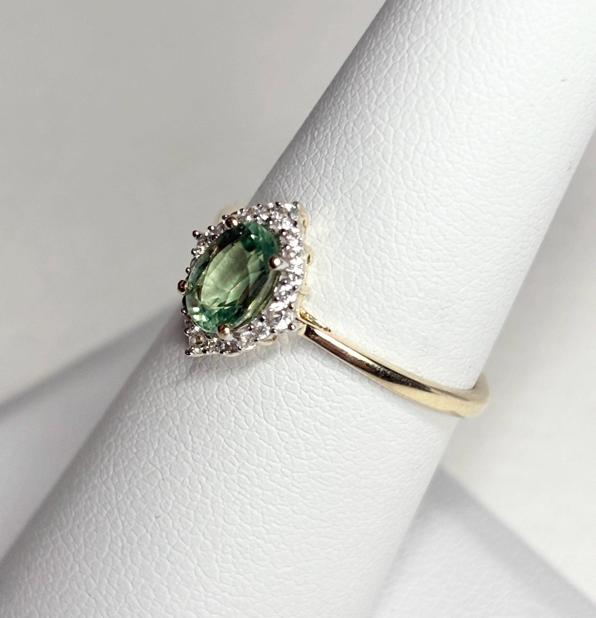 A 9k gold ring with a mint green kyanite center stone and a zircon halo.