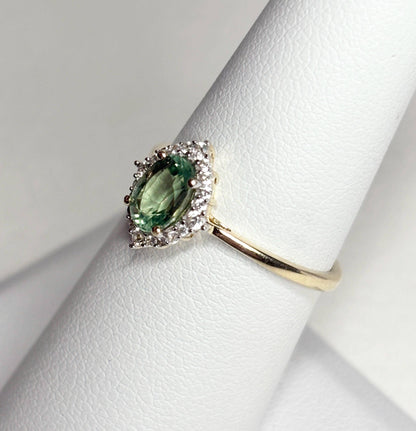 A 9k gold ring with a mint green kyanite center stone and a zircon halo.