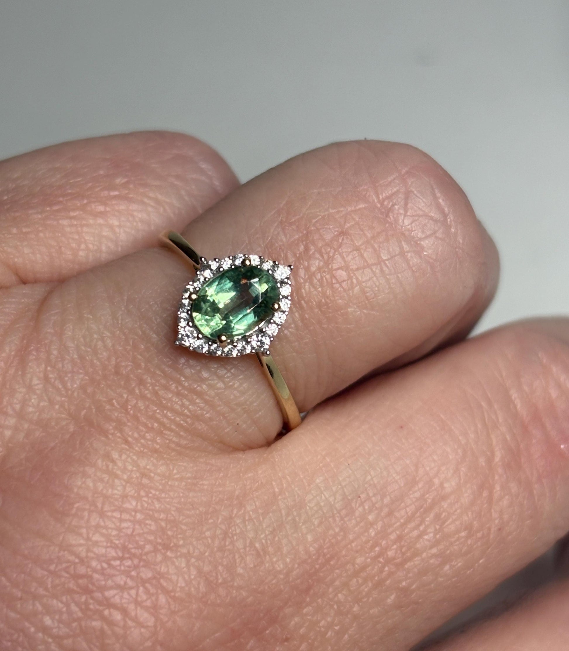 A 9k gold ring with a mint green kyanite center stone and a zircon halo.