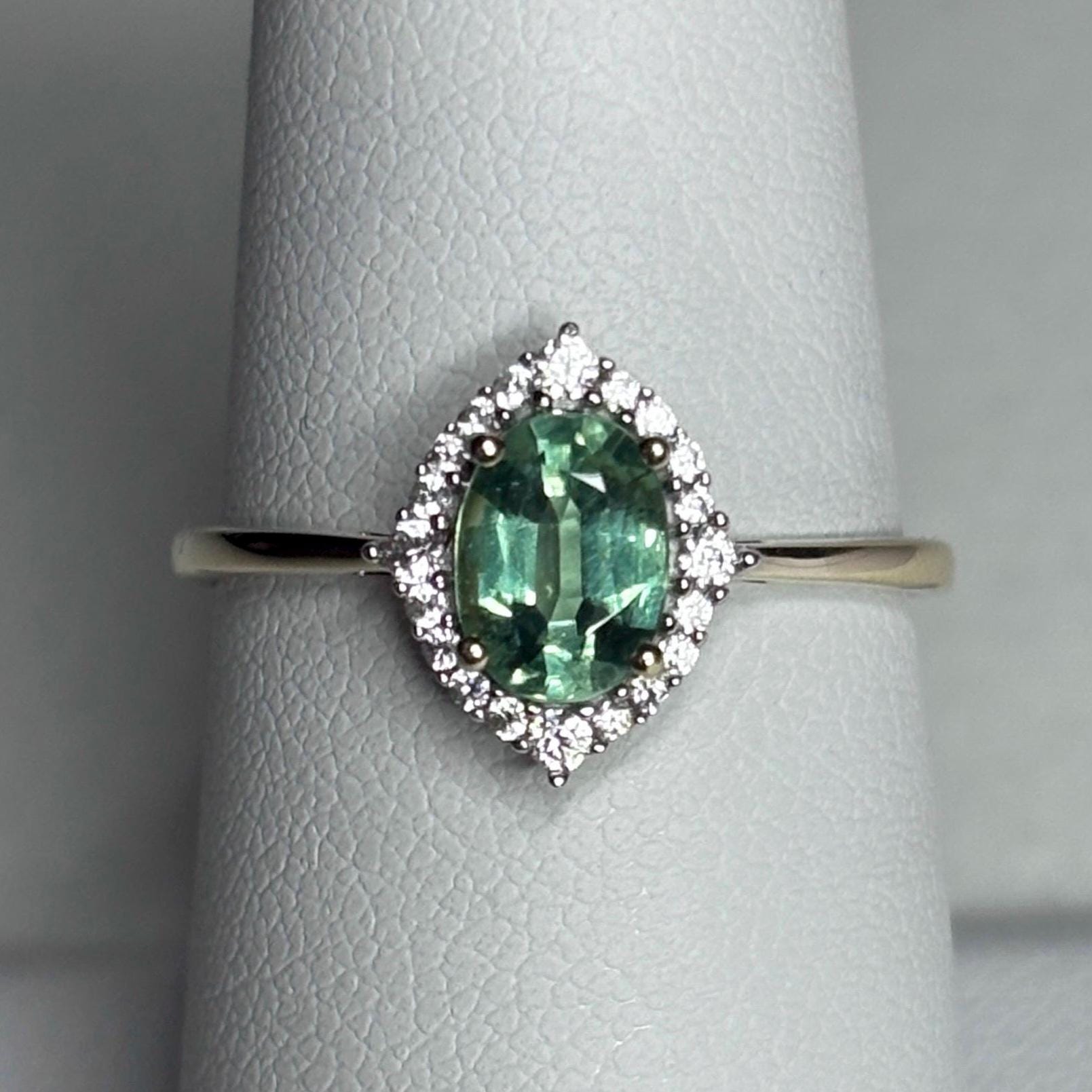 A mint green kyanite ring with a zircon halo in 9k gold.