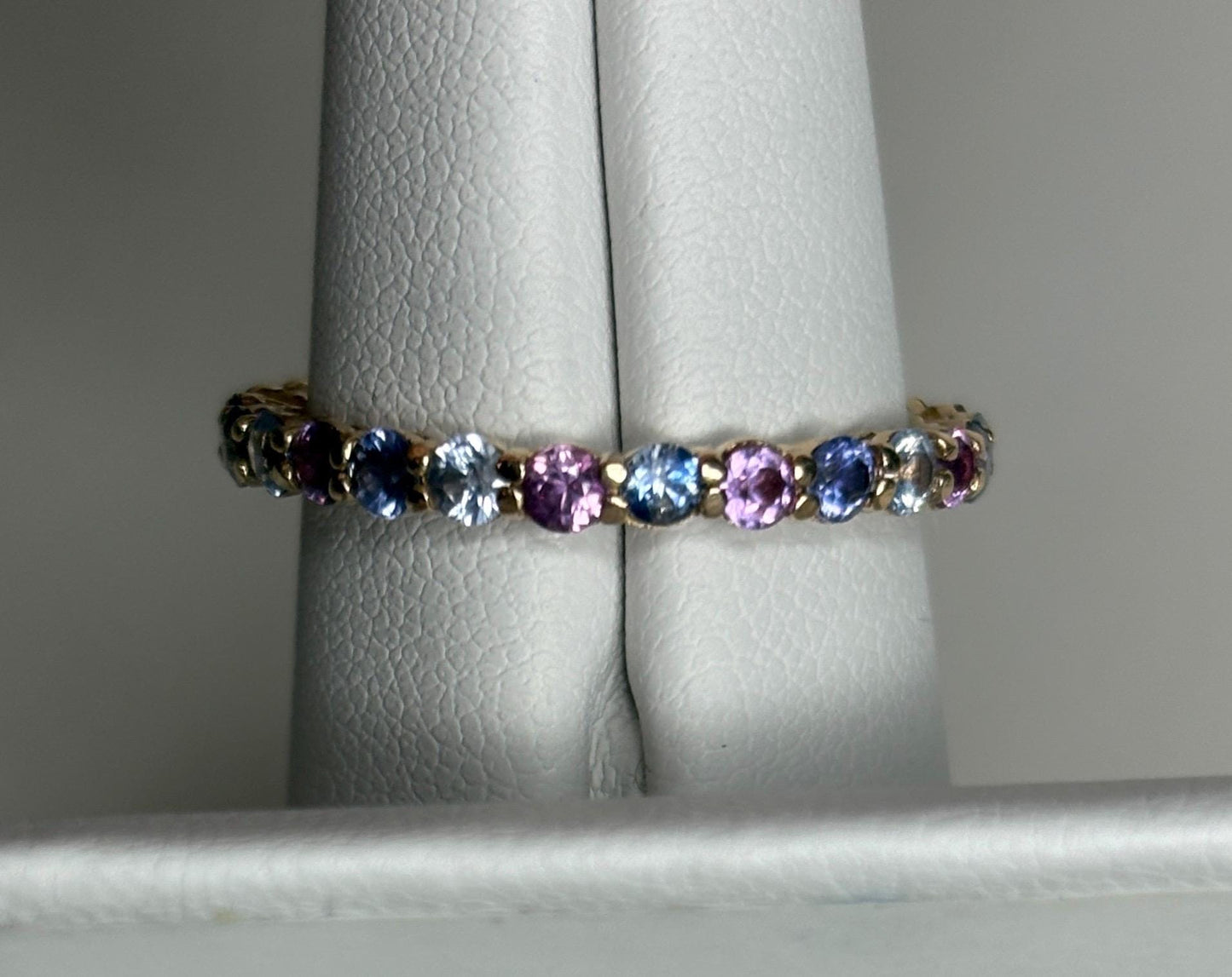 14k gold eternity band with alternating blue, pink, and violet sapphires.