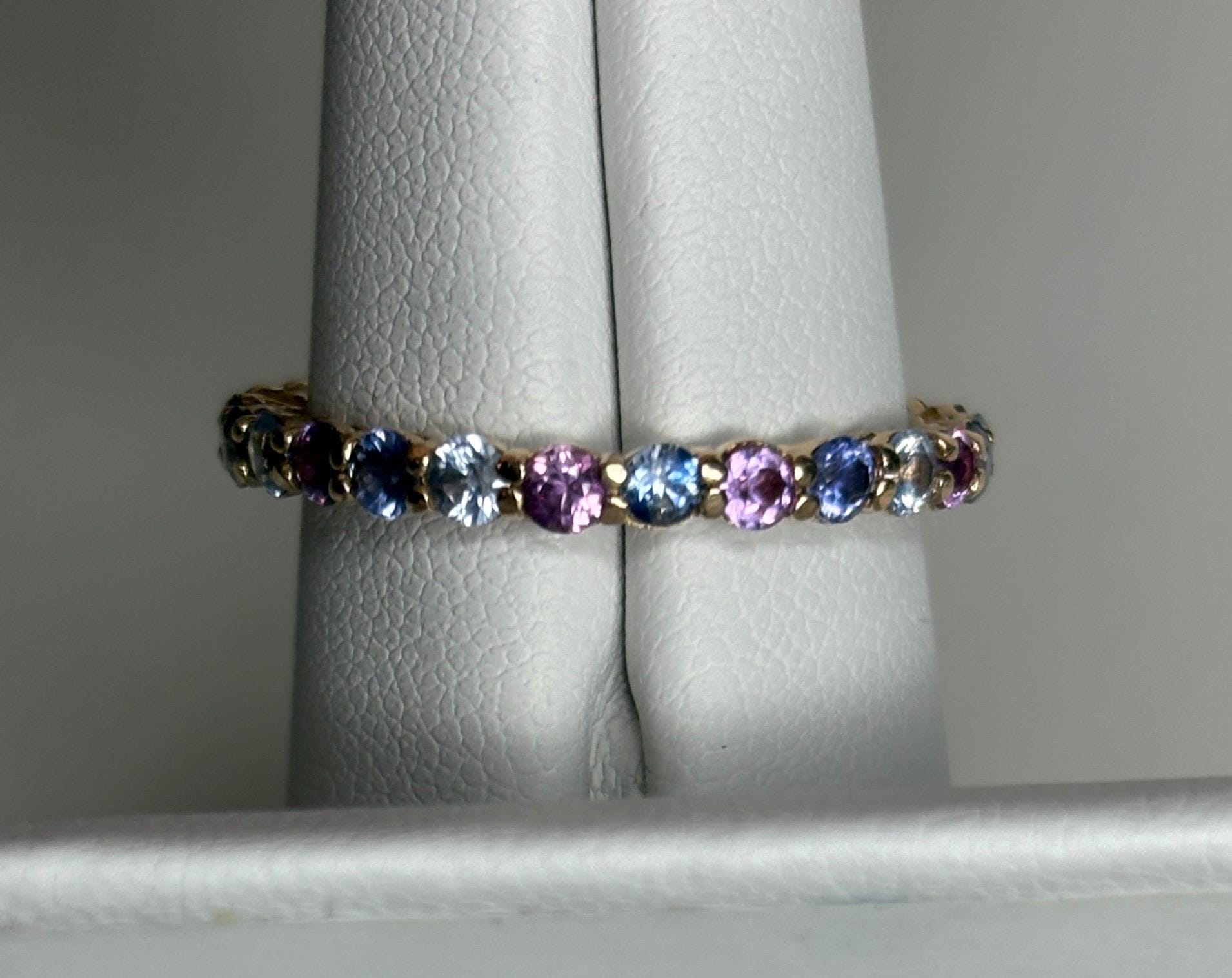 14k gold eternity band with alternating blue, pink, and violet sapphires.