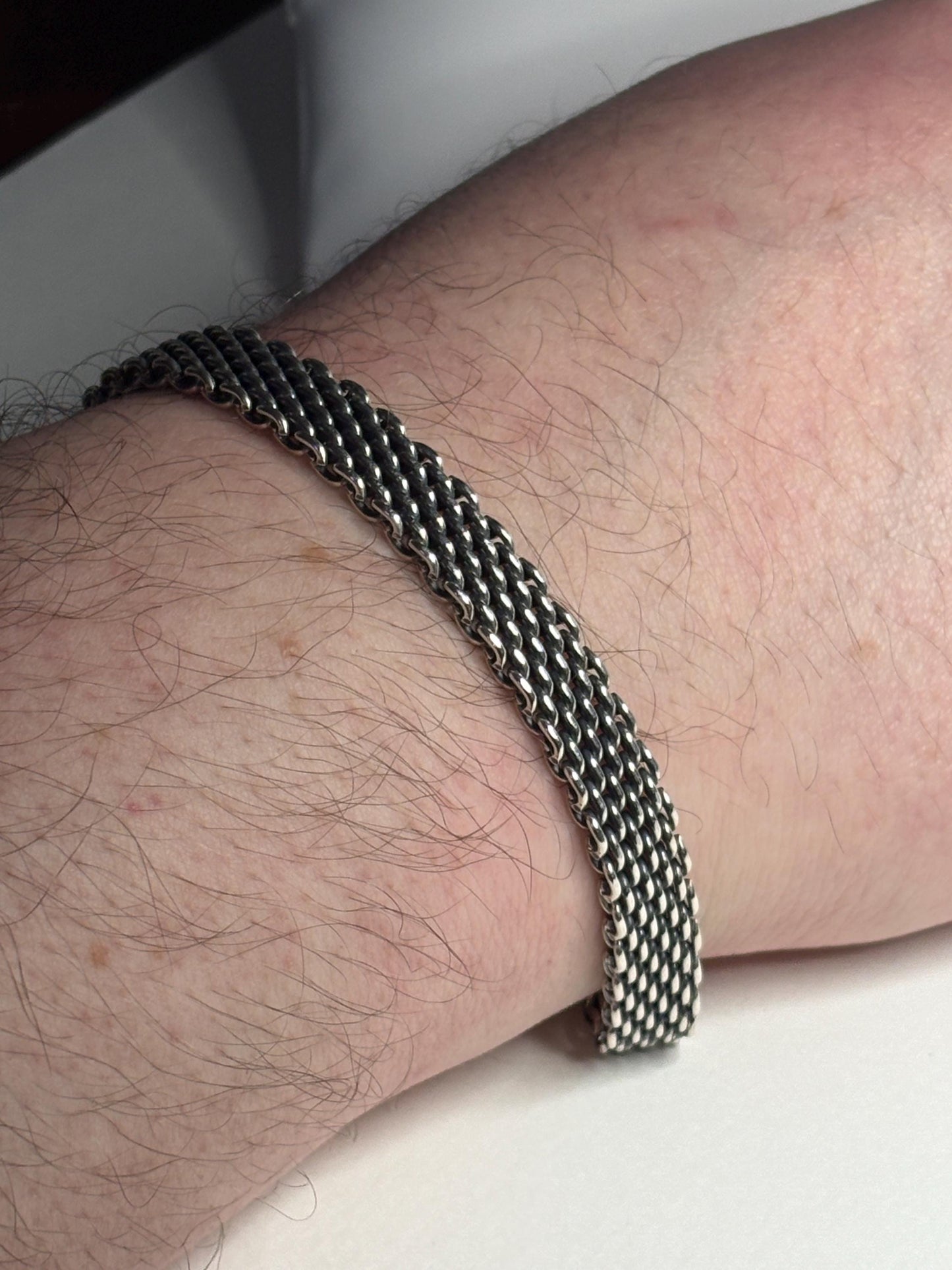 Sterling silver mesh bracelet with lobster claw clasp on a hairy arm.