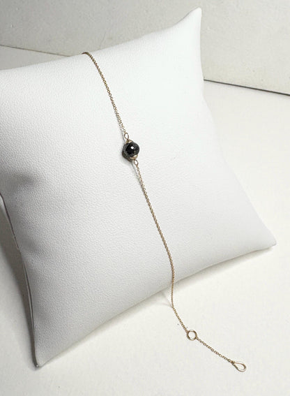 Solid 14k gold bracelet with a single faceted black diamond bead.