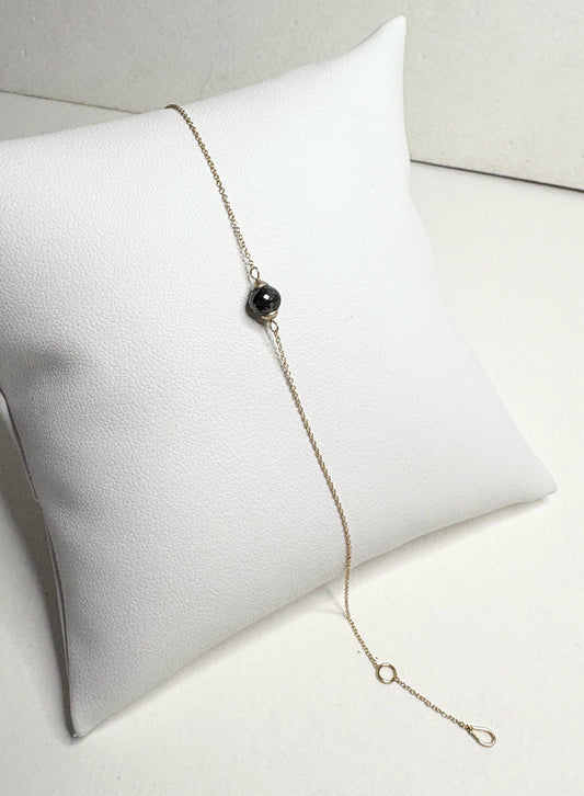Solid 14k gold bracelet with a single faceted black diamond bead.