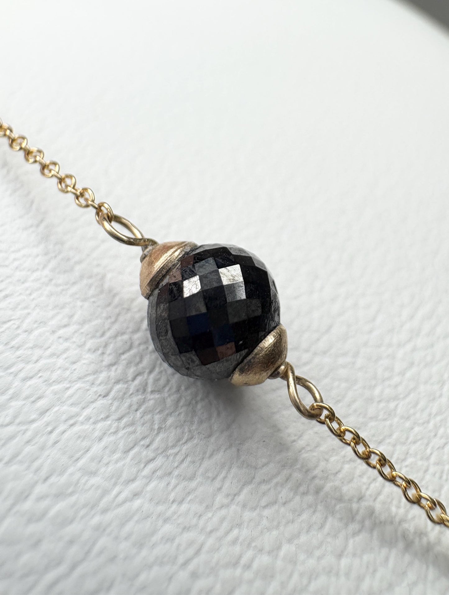 Solid 14k gold bracelet with a faceted black diamond bead.