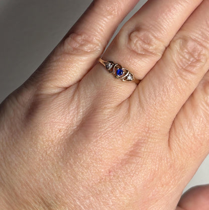 A vintage 10k gold heart band ring with a blue sapphire and two diamonds.
