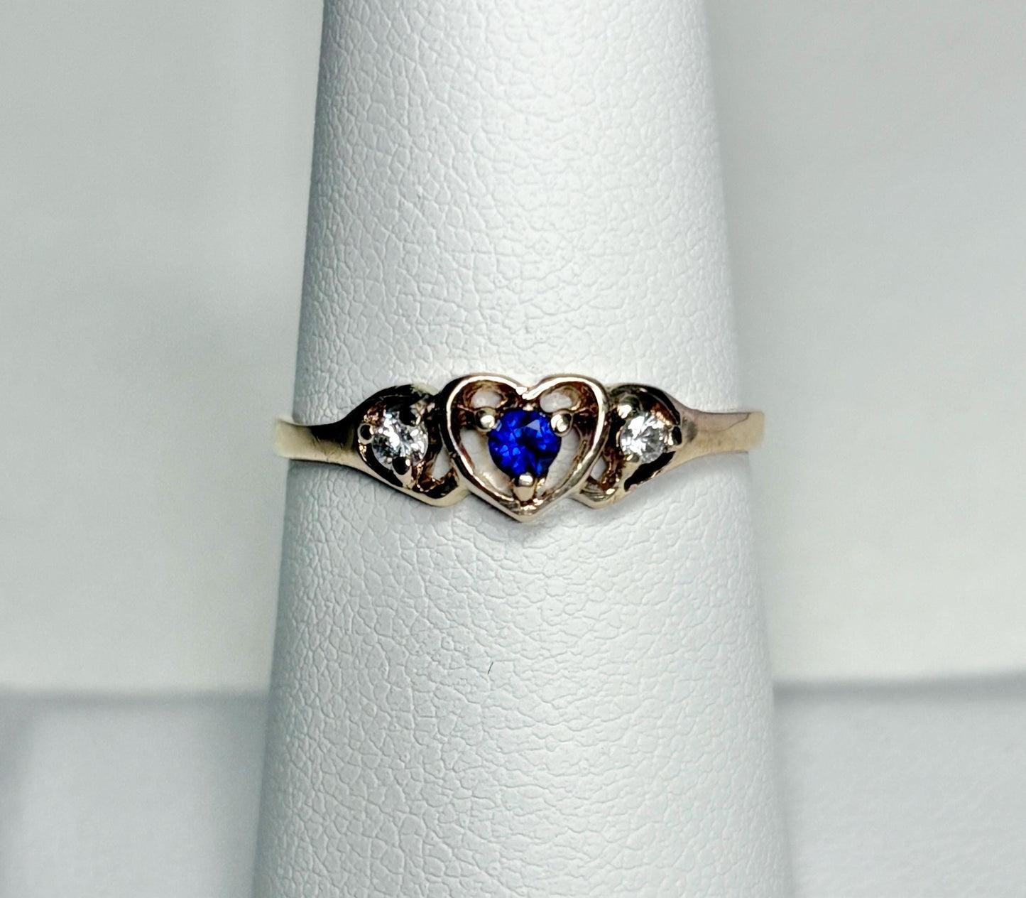 A vintage 10k gold heart band ring with a blue sapphire and two diamonds.