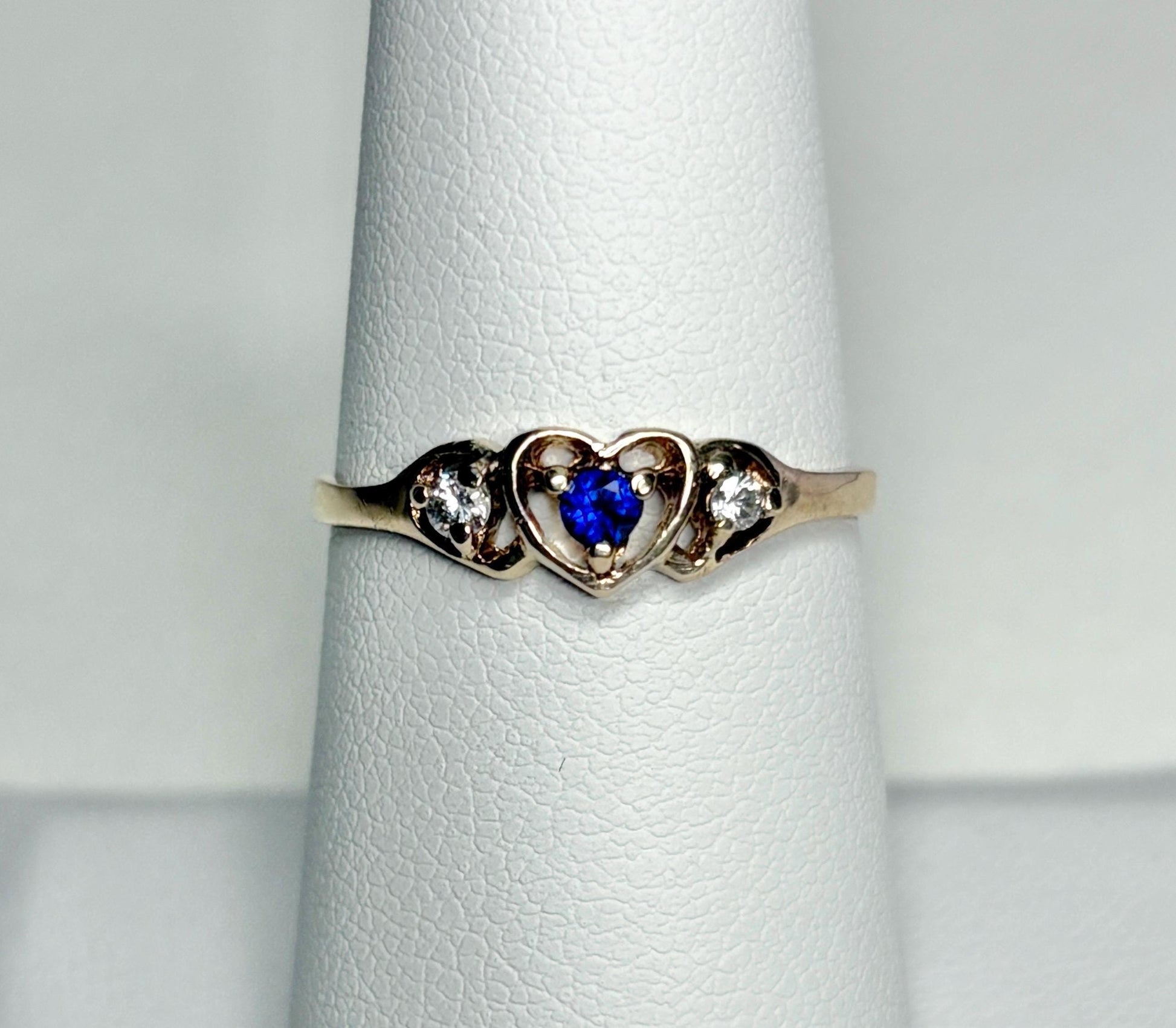 A vintage 10k gold heart band ring with a blue sapphire and two diamonds.