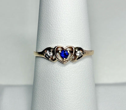 A vintage 10k gold heart band ring with a blue sapphire and two diamonds.