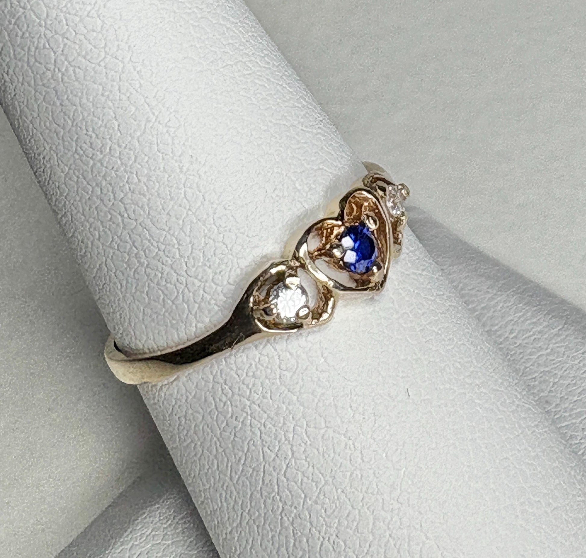A vintage 10k gold ring with a sapphire and two diamonds in a heart design.