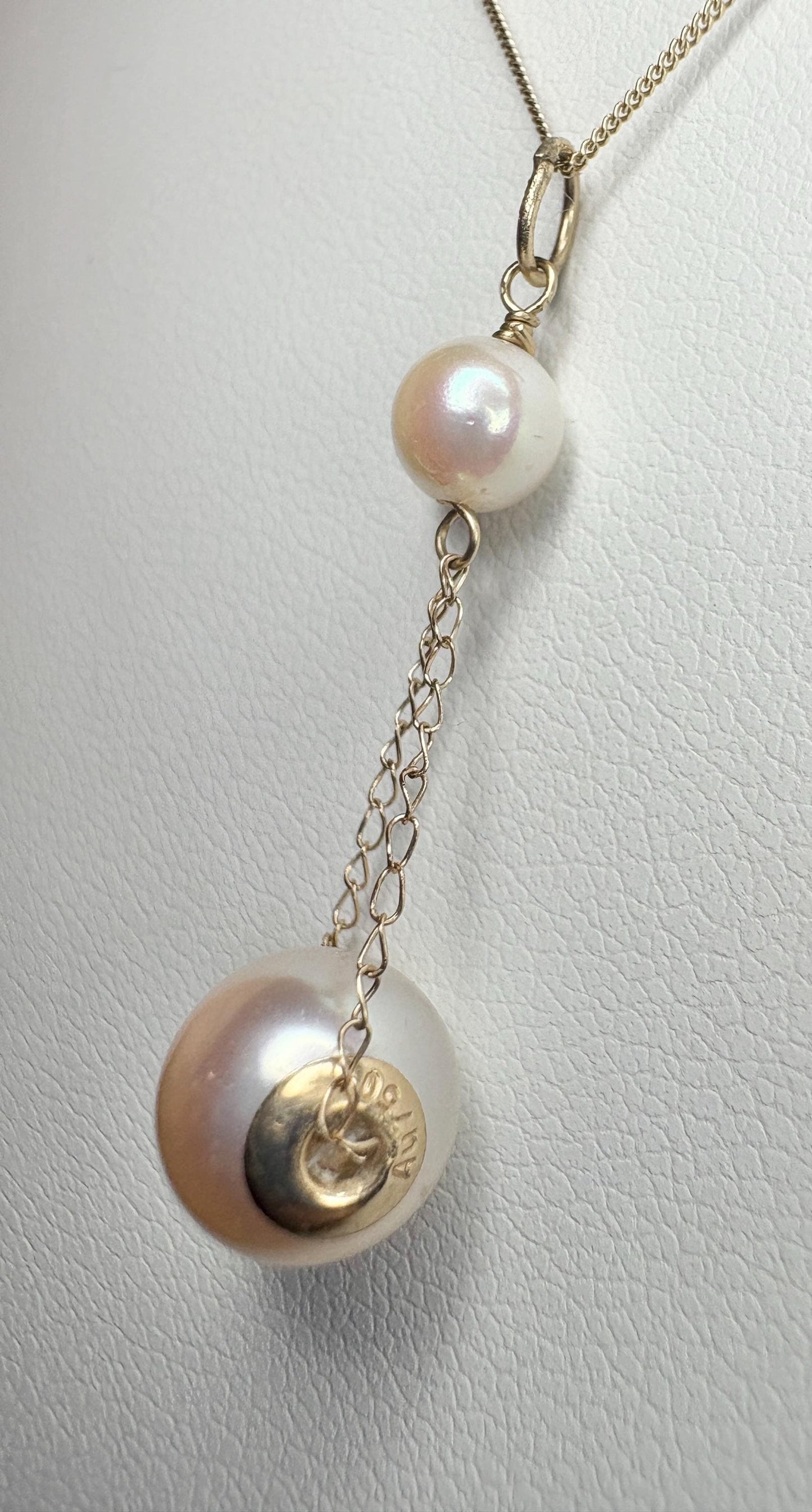 A gold lavaliere pendant necklace with two Akoya pearls and a gold disc.