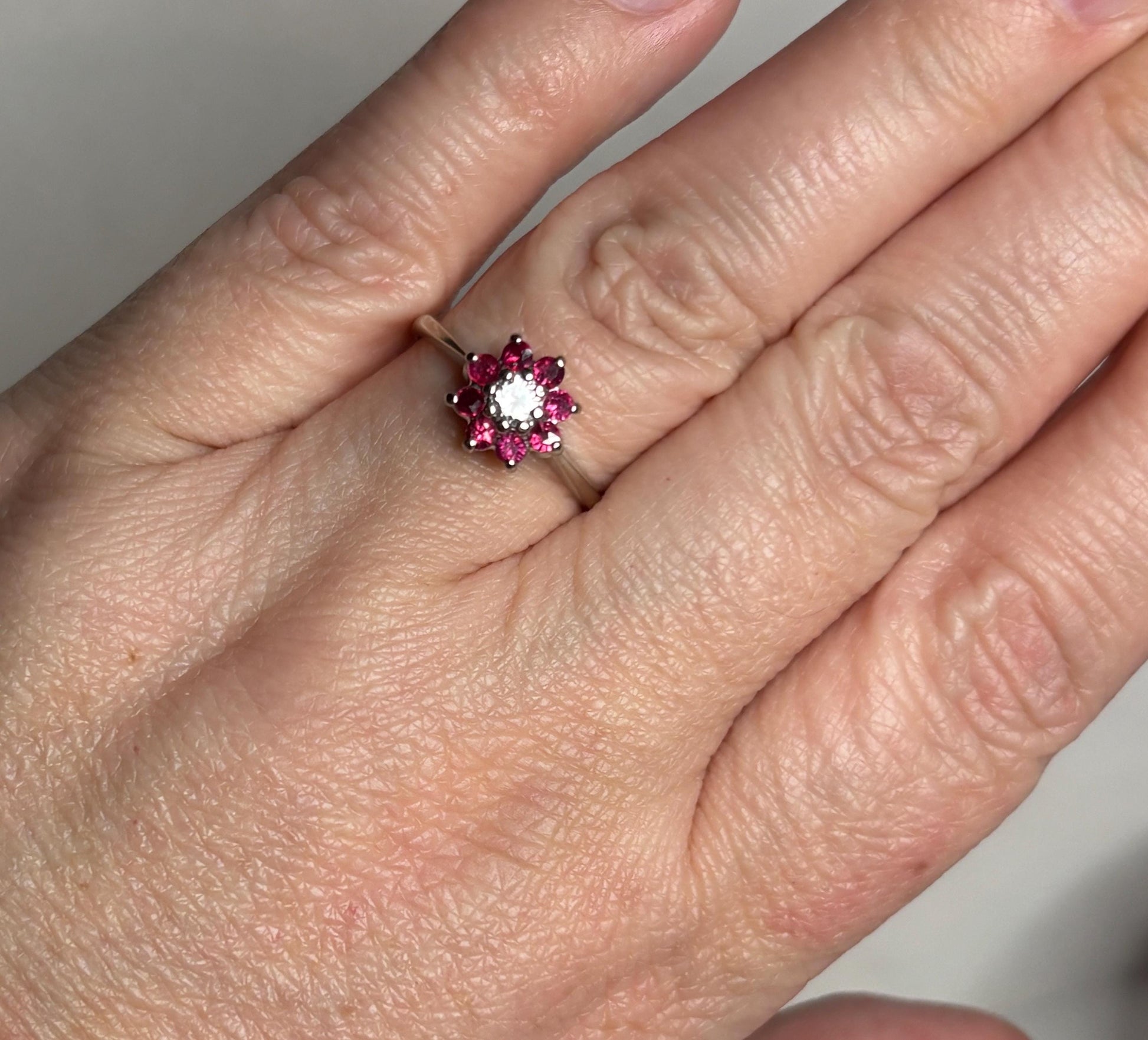 Natural ruby and diamond daisy halo ring in 14k white gold.