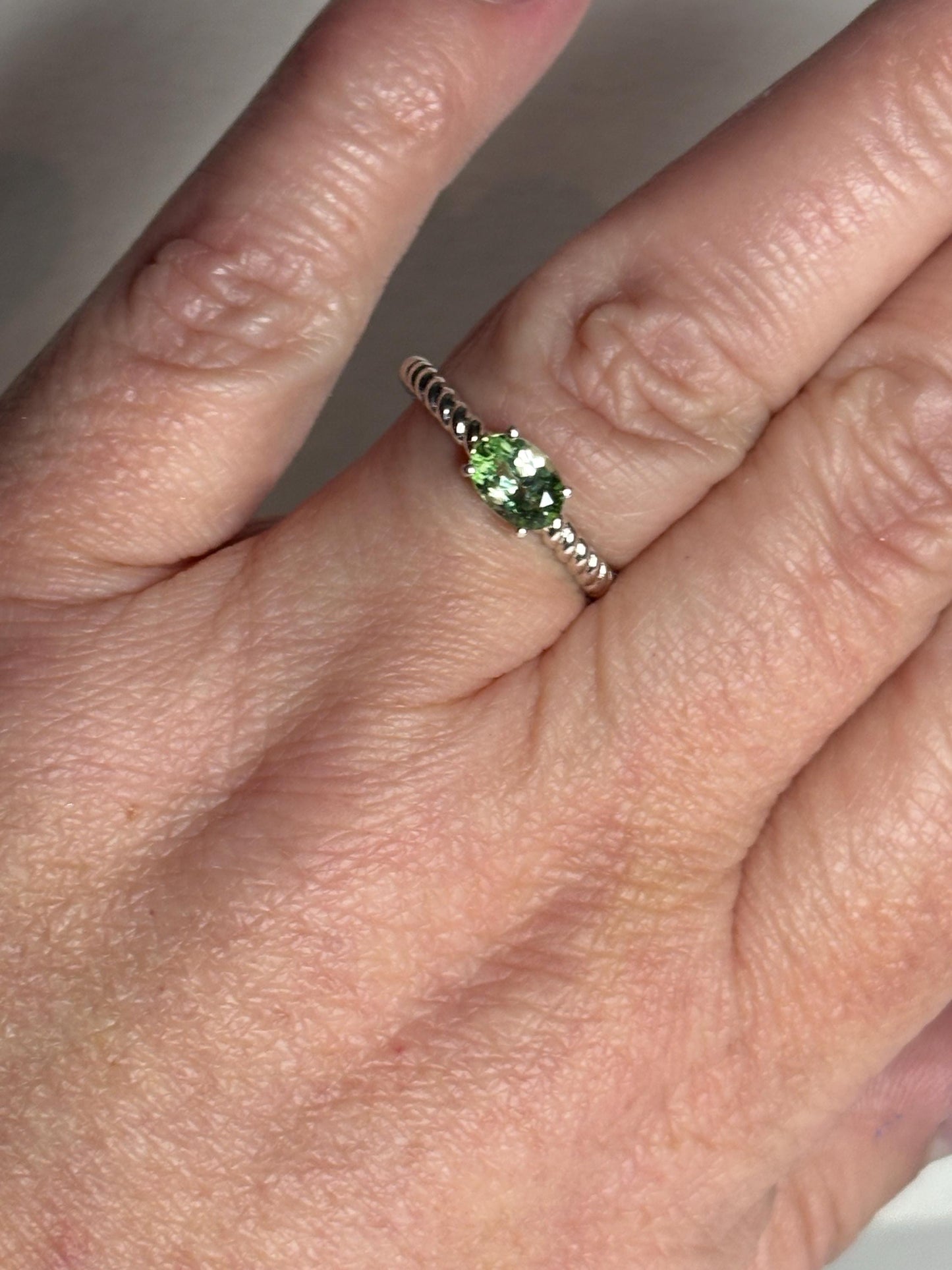 Sterling silver ring with an oval green tourmaline in an east-west setting on a rope band.
