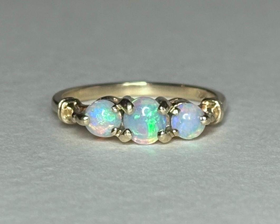 A 14k gold ring with three oval opals.