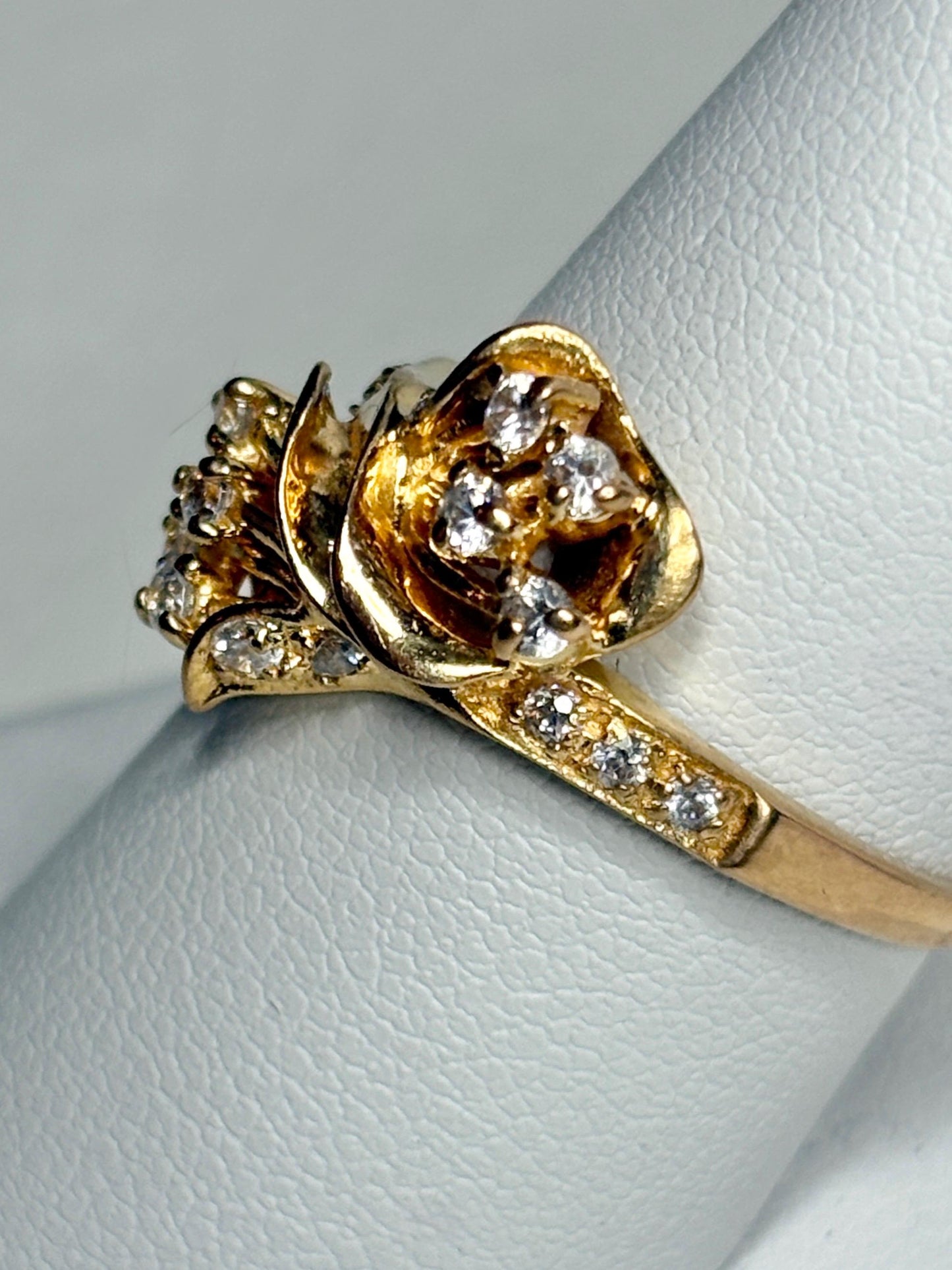 Solid 21k gold lily bypass ring with white stones.