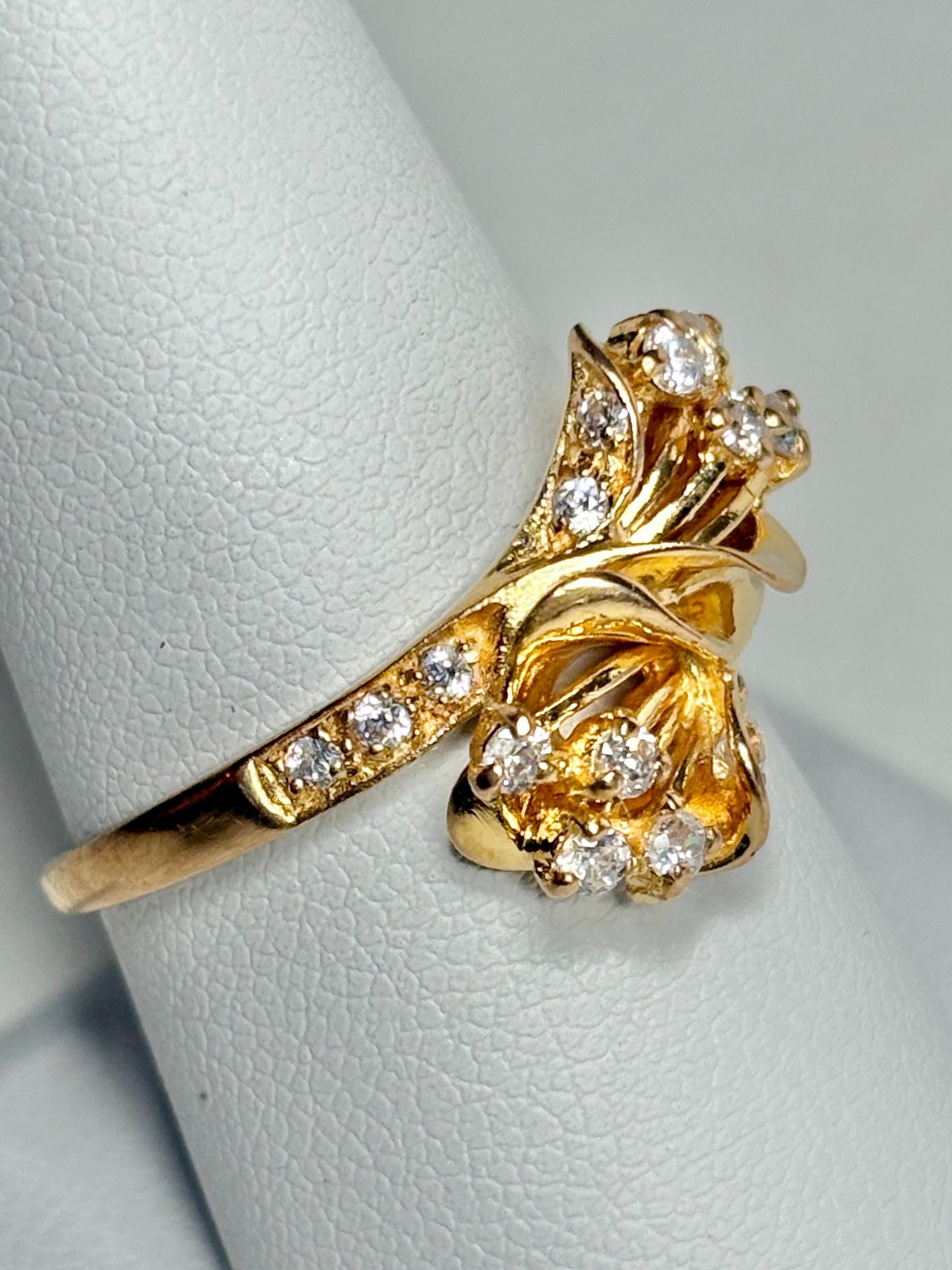 Solid 21k gold lily bypass ring with white stones.