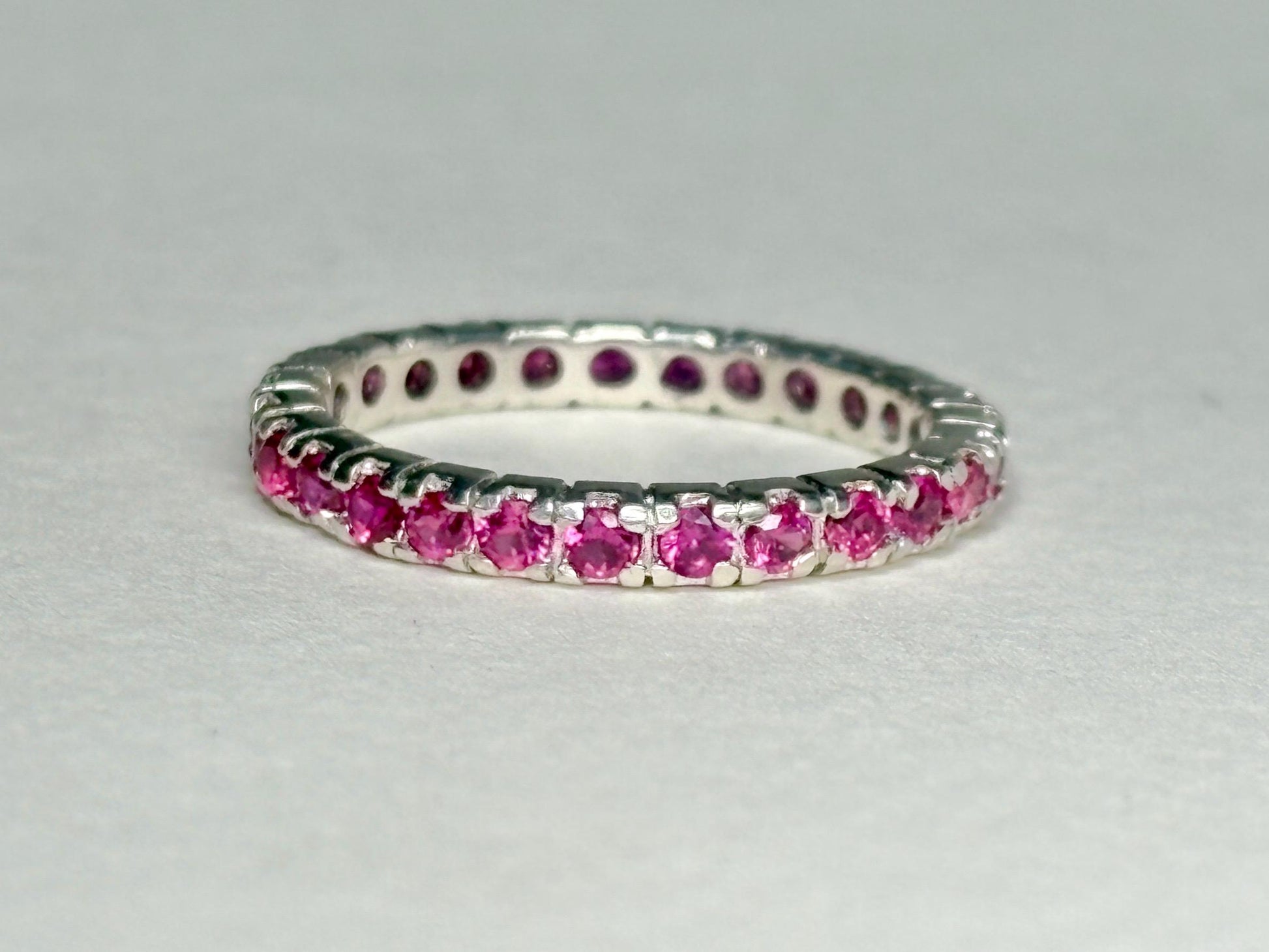 Hot pink lab-grown sapphire eternity ring in solid sterling silver.