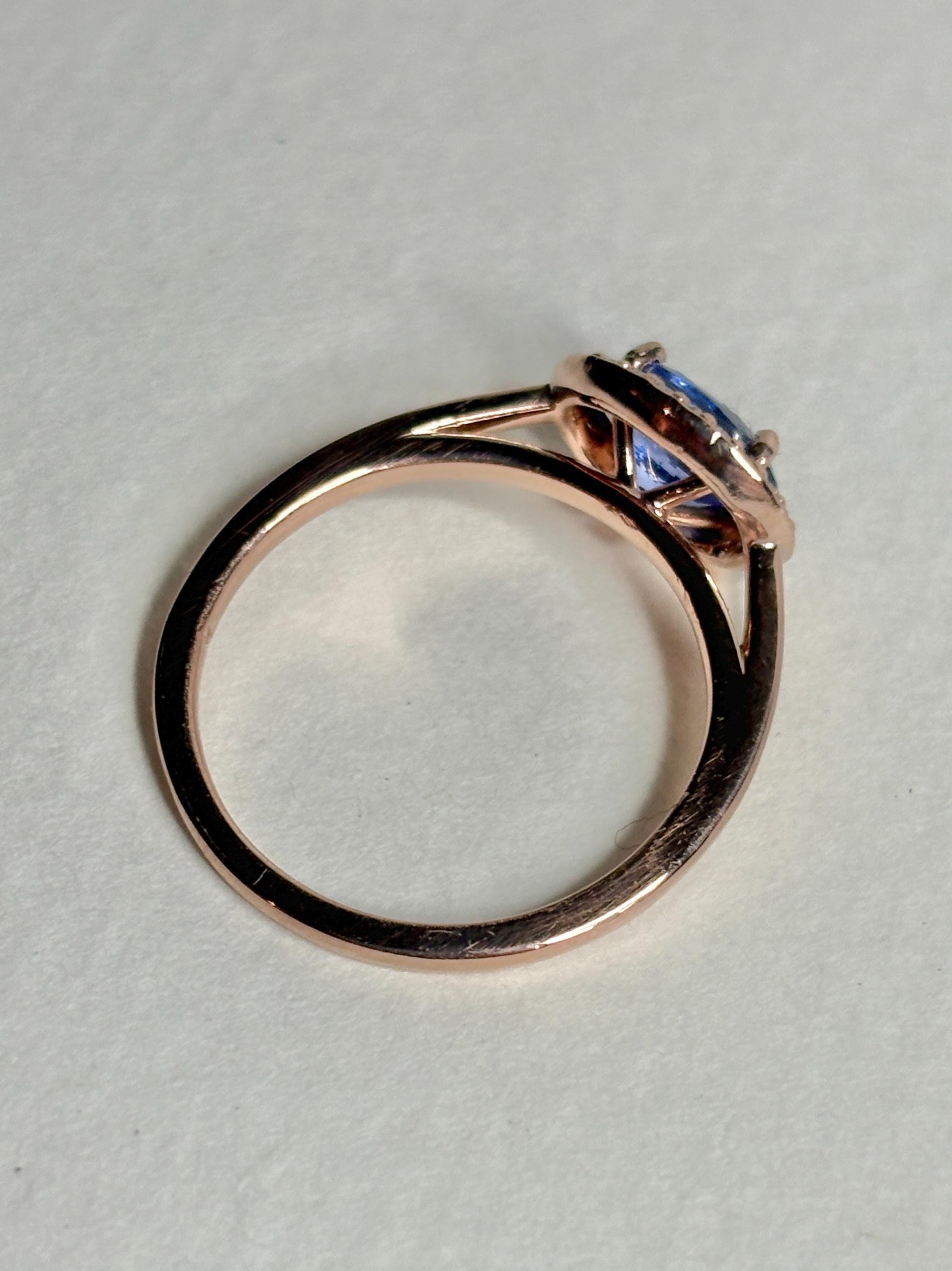 A rose gold ring with a tanzanite center stone and diamond halo.