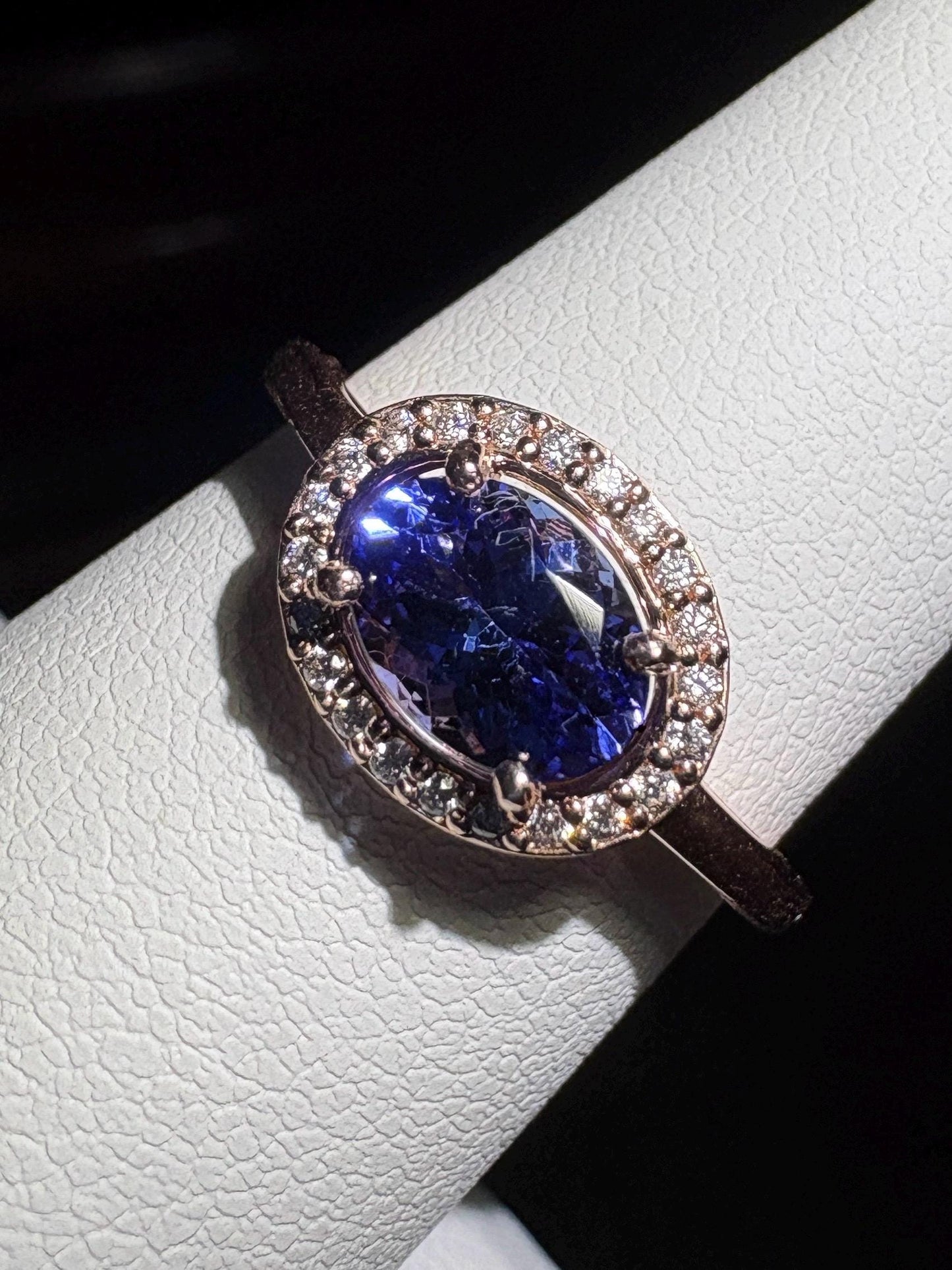 Oval tanzanite ring with diamond halo in rose gold.