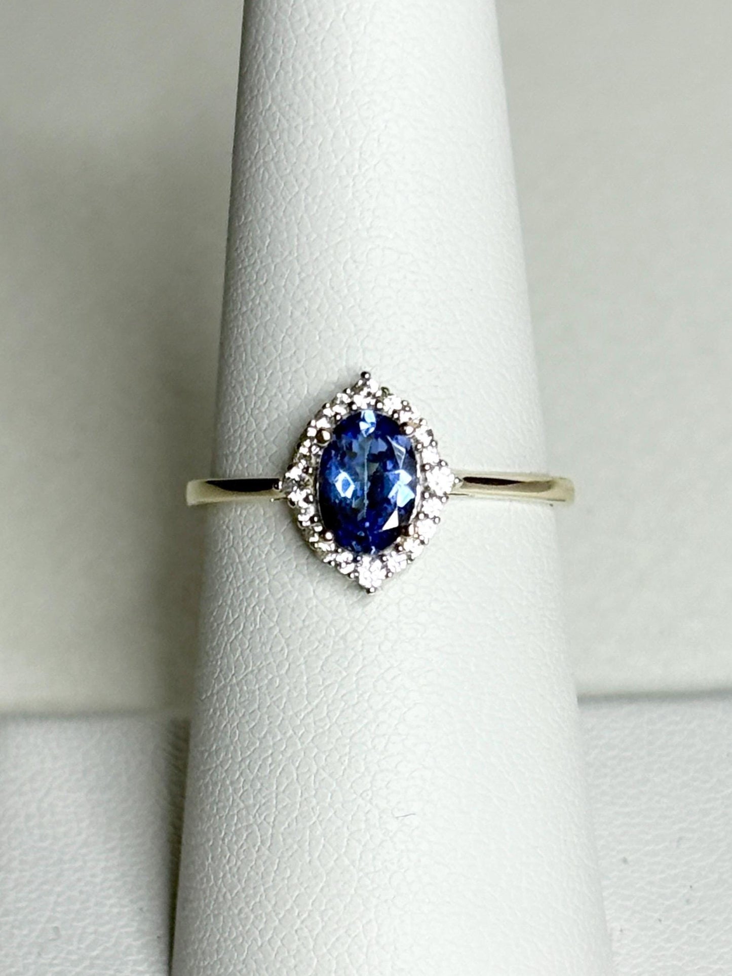 Oval tanzanite and zircon halo ring in 9k gold.