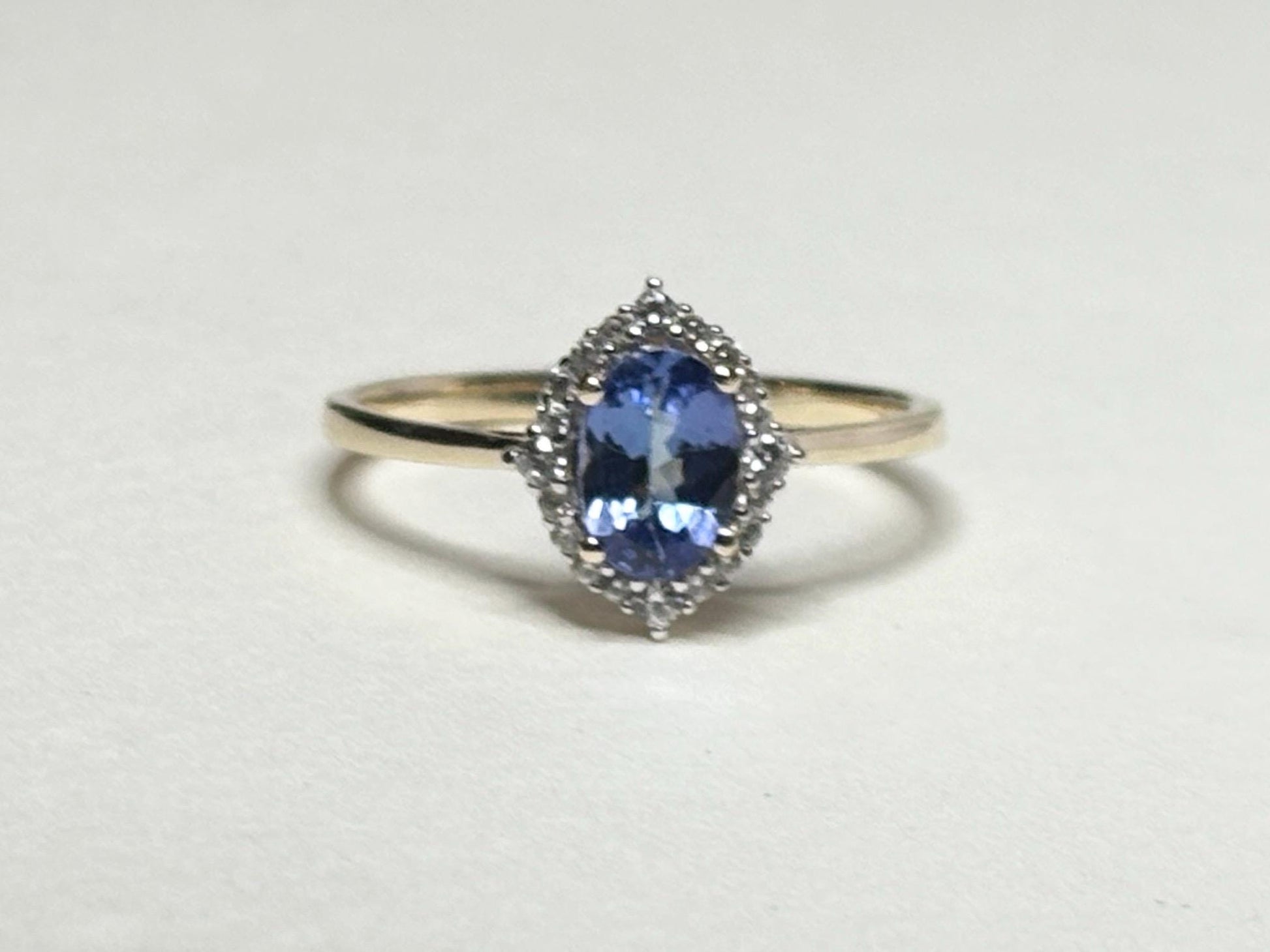 Oval tanzanite and zircon halo ring in solid 9k gold.