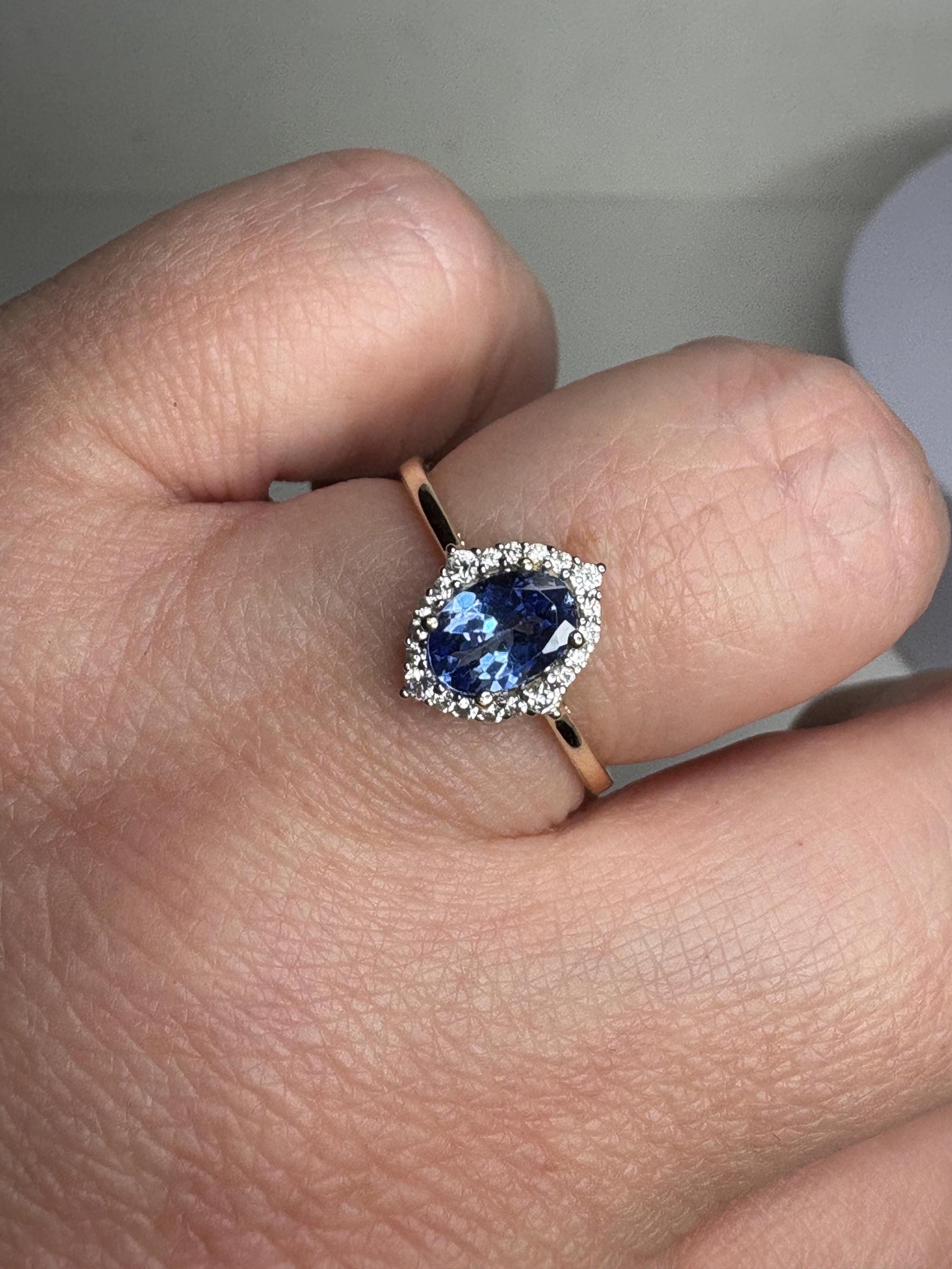 Oval tanzanite and zircon halo ring in 9k gold.