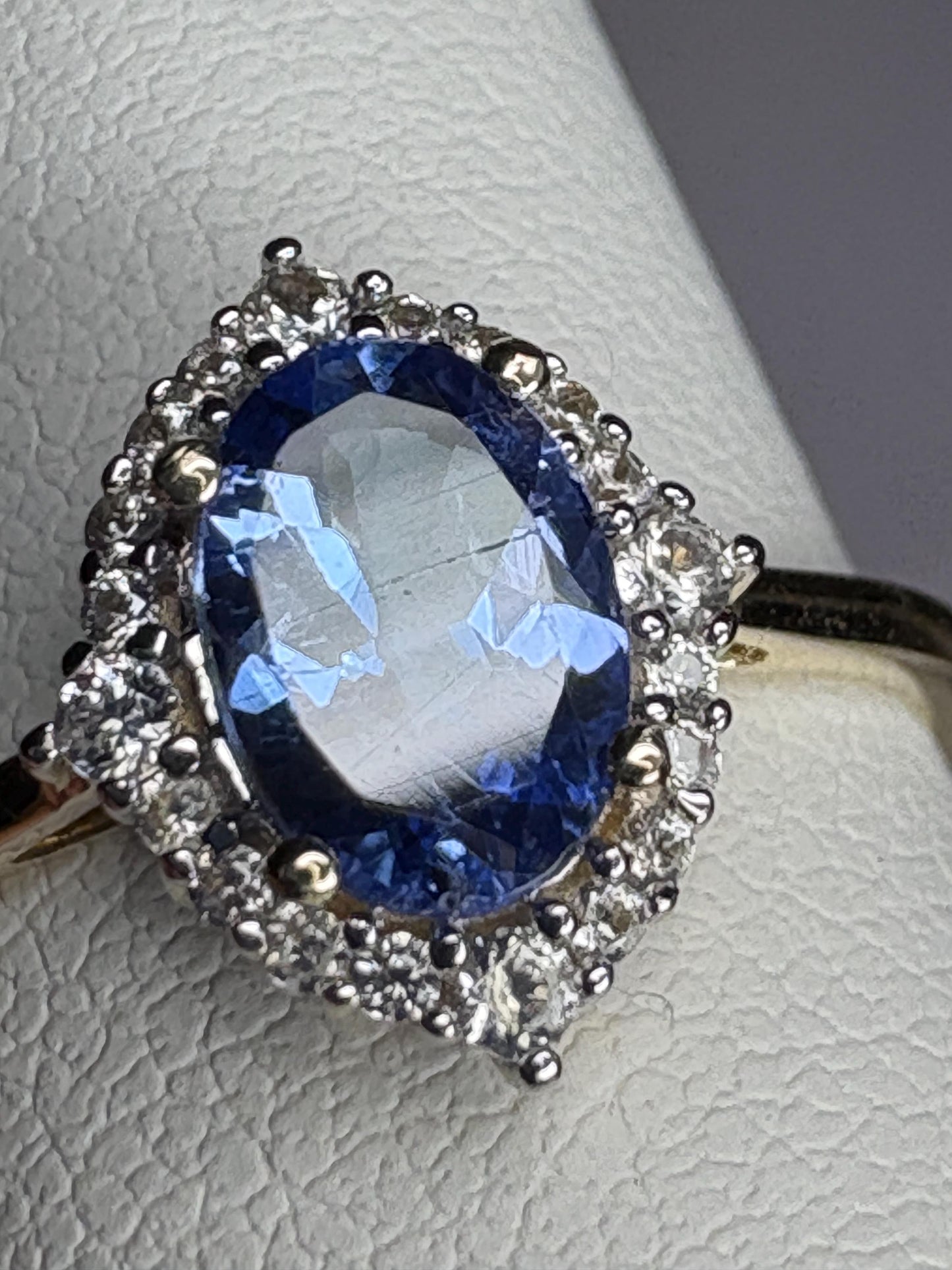 Oval tanzanite and zircon halo ring in 9k gold.