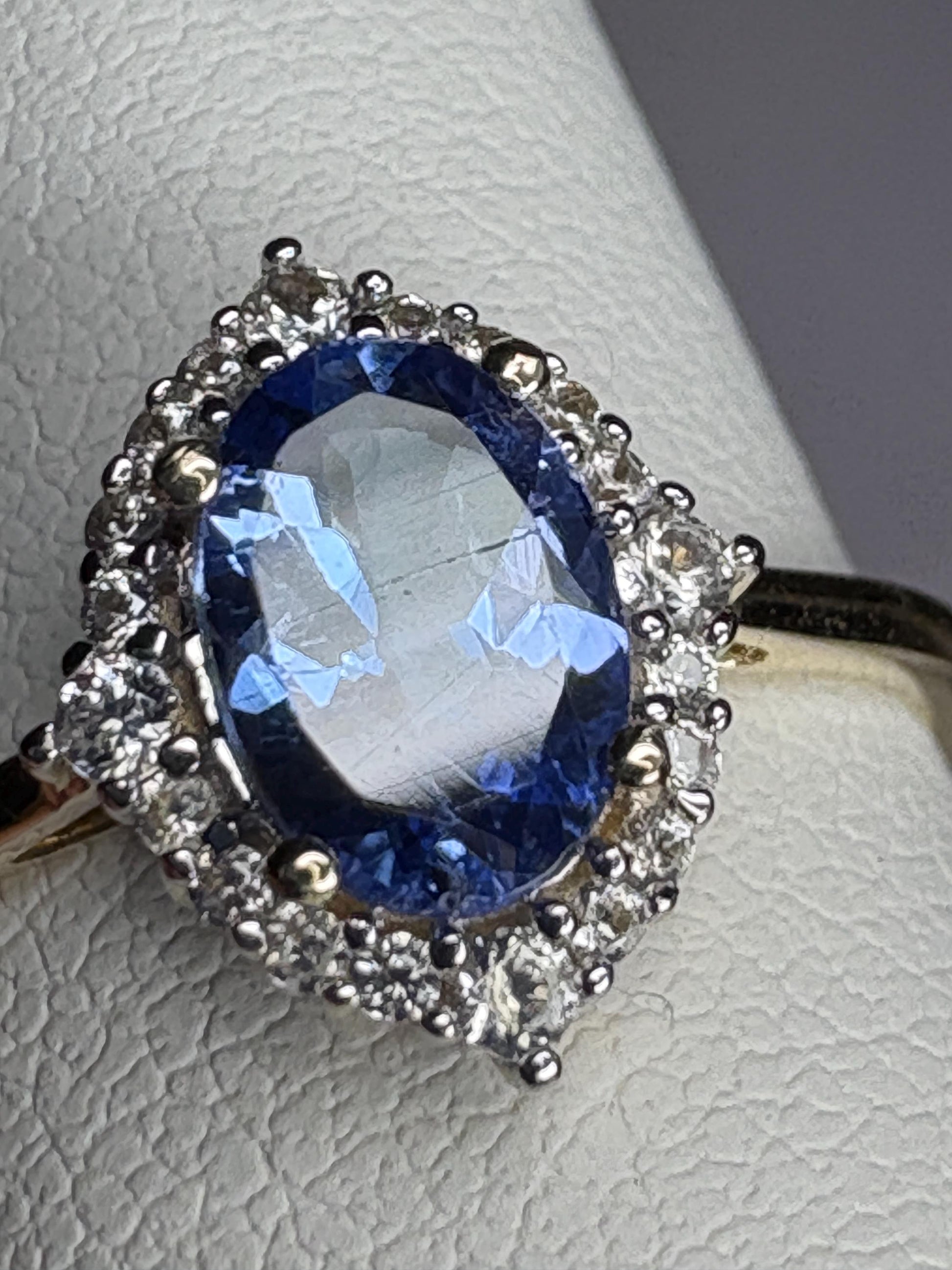 Oval tanzanite and zircon halo ring in 9k gold.