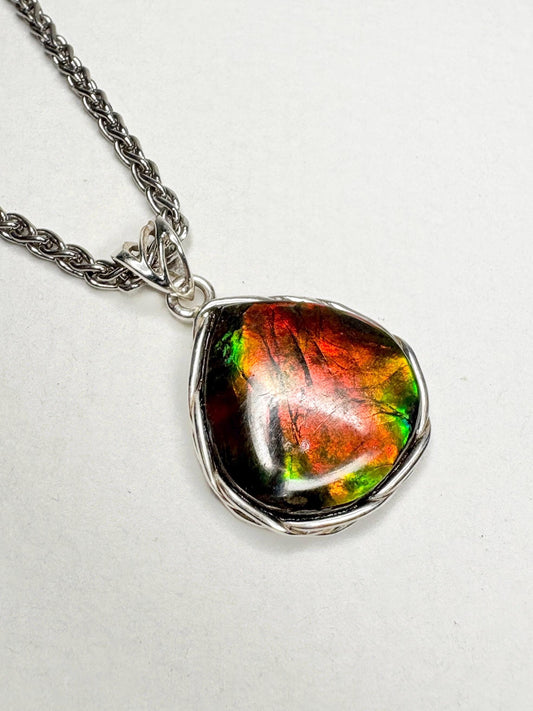 Natural ammolite pendant necklace with braided sterling silver bezel on a wheat chain.