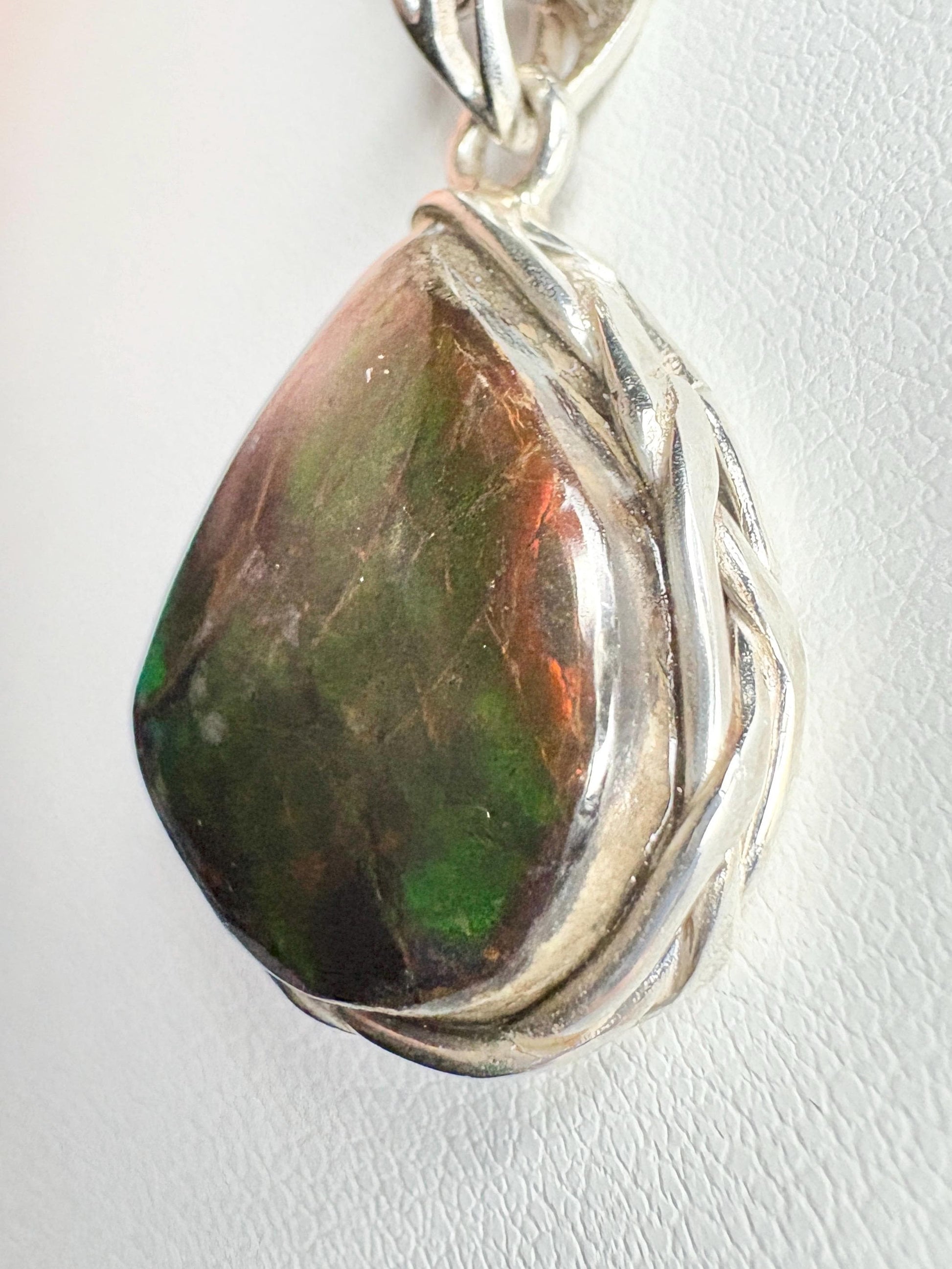 Natural ammolite pendant with braided sterling silver setting.