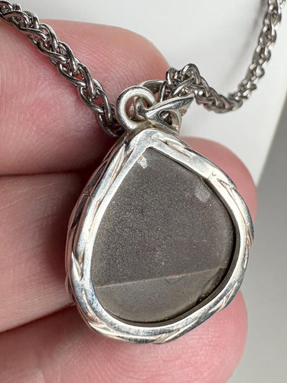 Sterling silver pendant necklace with a braided bezel holding a pear-shaped ammolite stone.