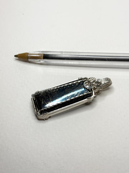 Wire wrapped covellite pendant in sterling silver with metallic luster.