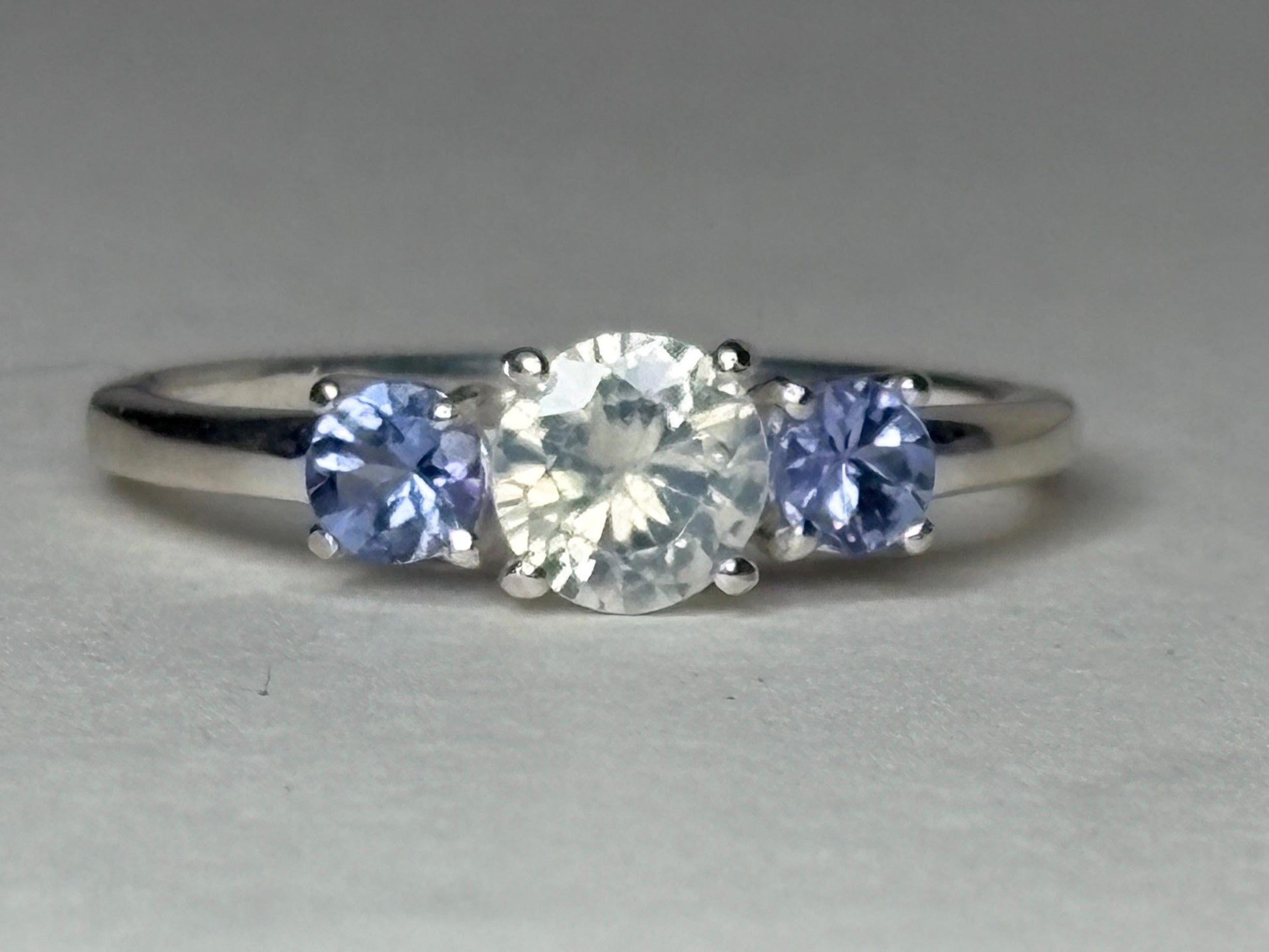 Sterling silver ring with a central off-white zircon and two tanzanite stones.