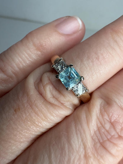 A 14k gold ring with a blue asscher cut tourmaline and two princess cut diamonds.