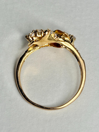 Solid 21k gold lily bypass ring with white stones.