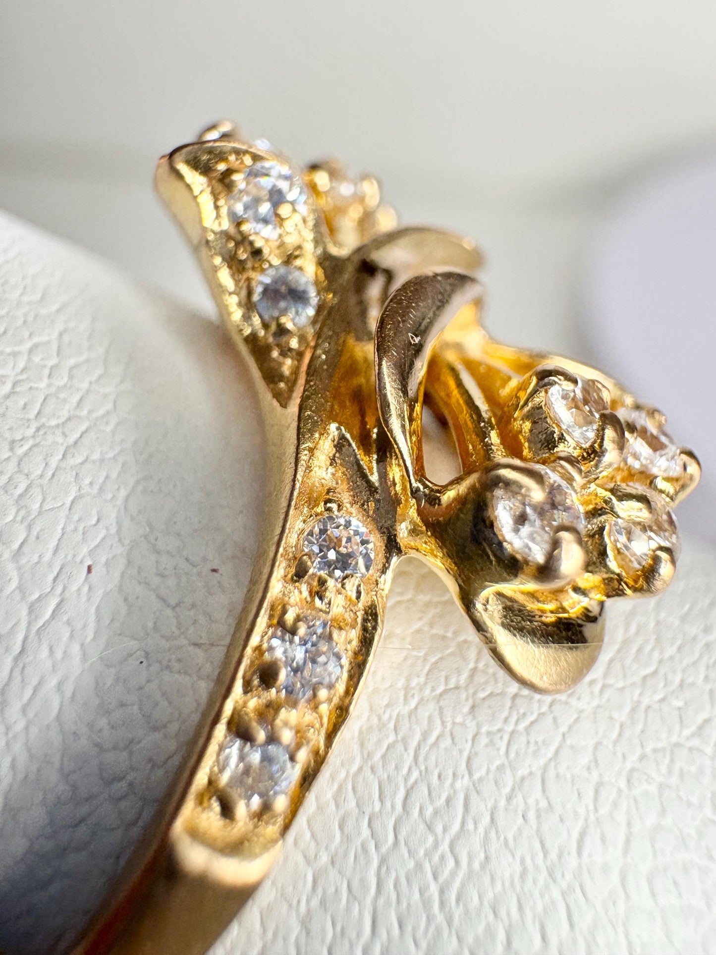 Solid 21k gold lily bypass ring with white stones.