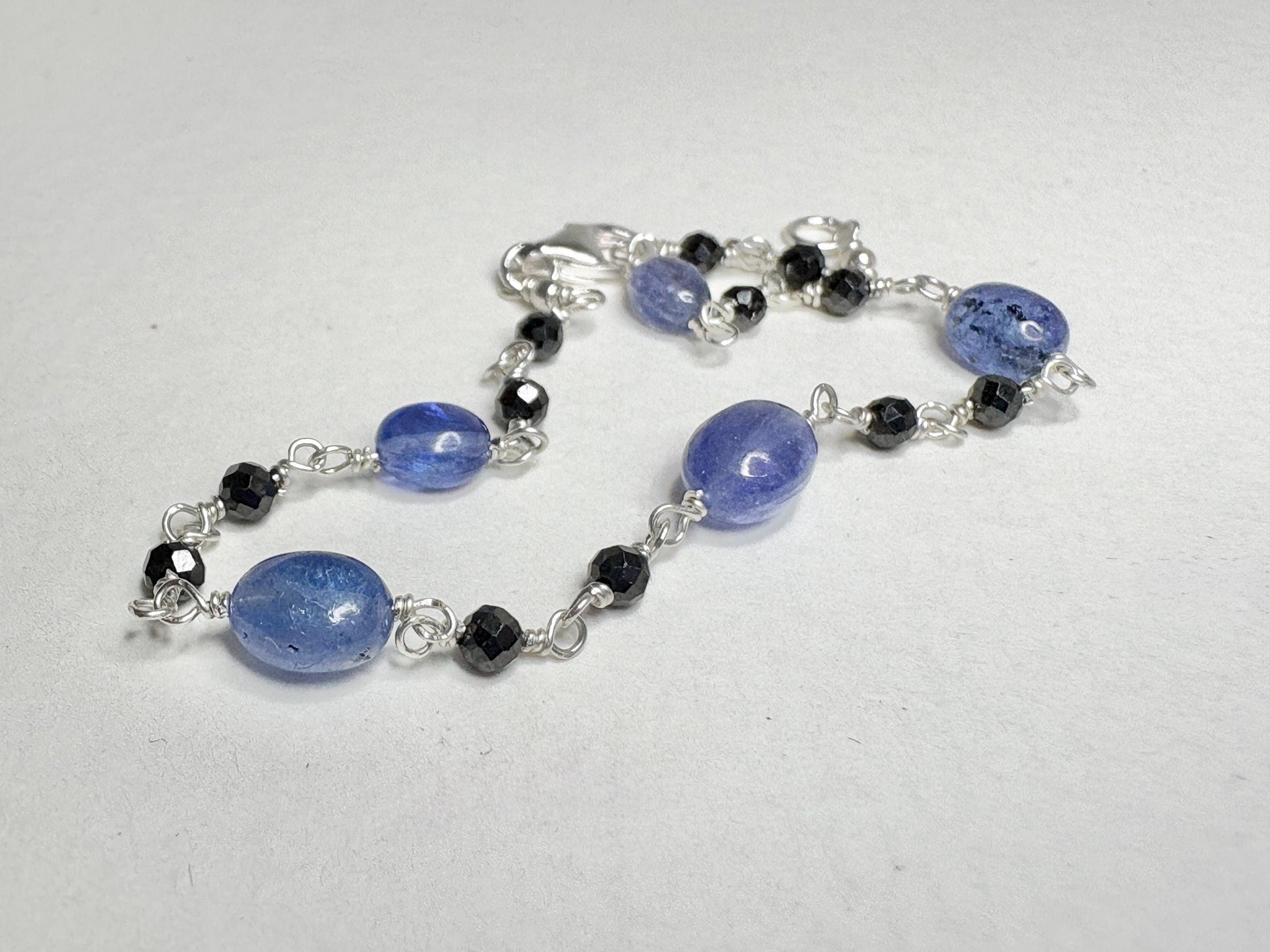 Sterling silver bracelet with oval tanzanite and faceted black diamond beads.