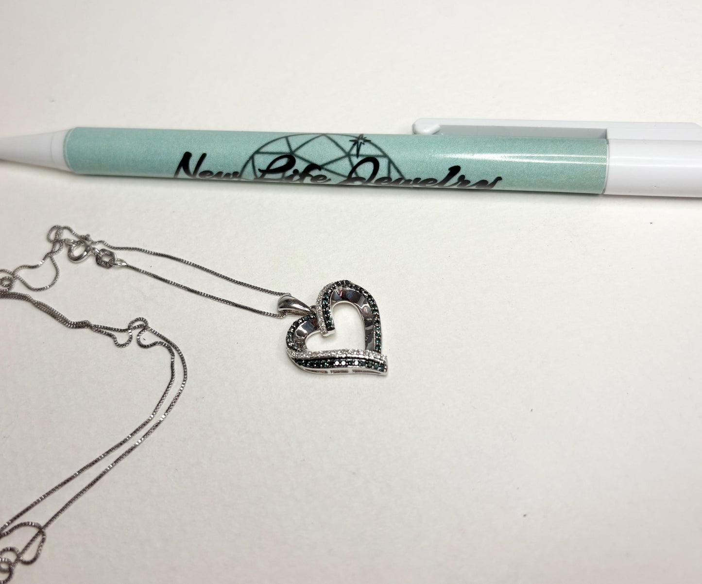 Sterling silver necklace with a heart pendant featuring blue and white diamonds.