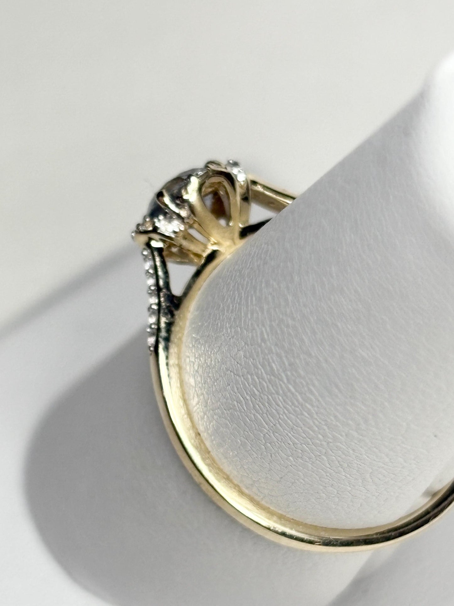 A 9k gold ring with a light greenish-blue Montana sapphire and white zircon accents.