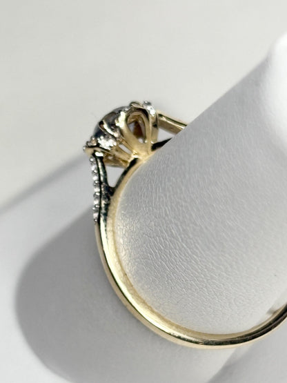 A 9k gold ring with a light greenish-blue Montana sapphire and white zircon accents.