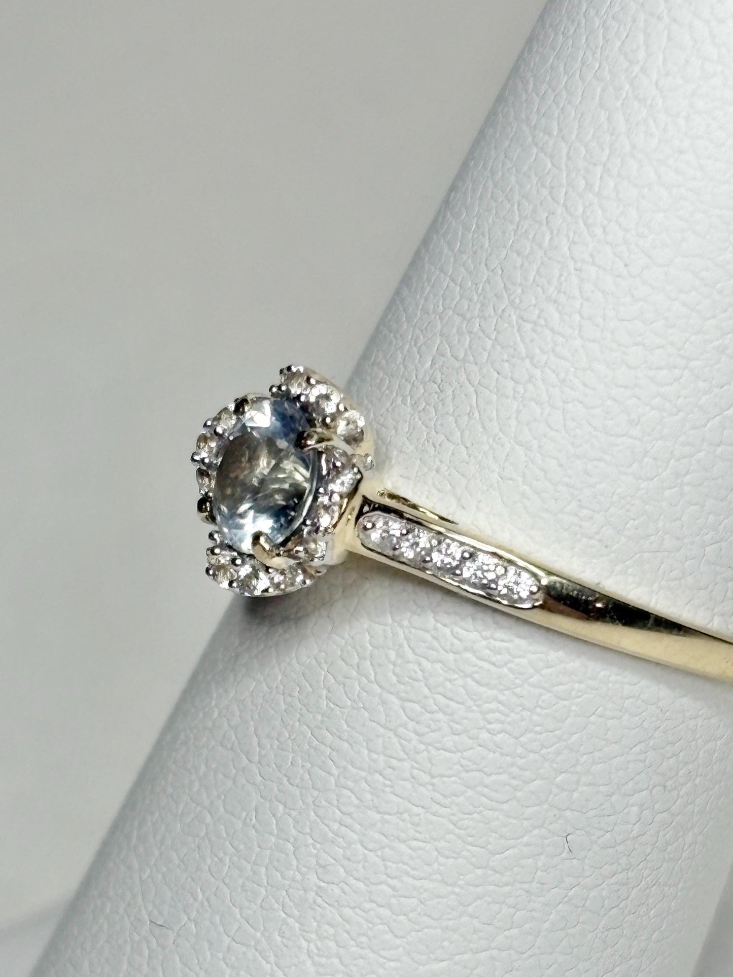 A 9k gold ring with a Montana sapphire and white zircon floral halo.