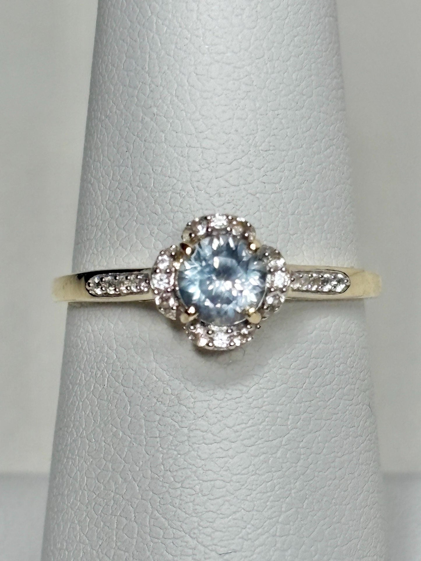 9k gold ring with a Montana sapphire and white zircon in a floral halo design.