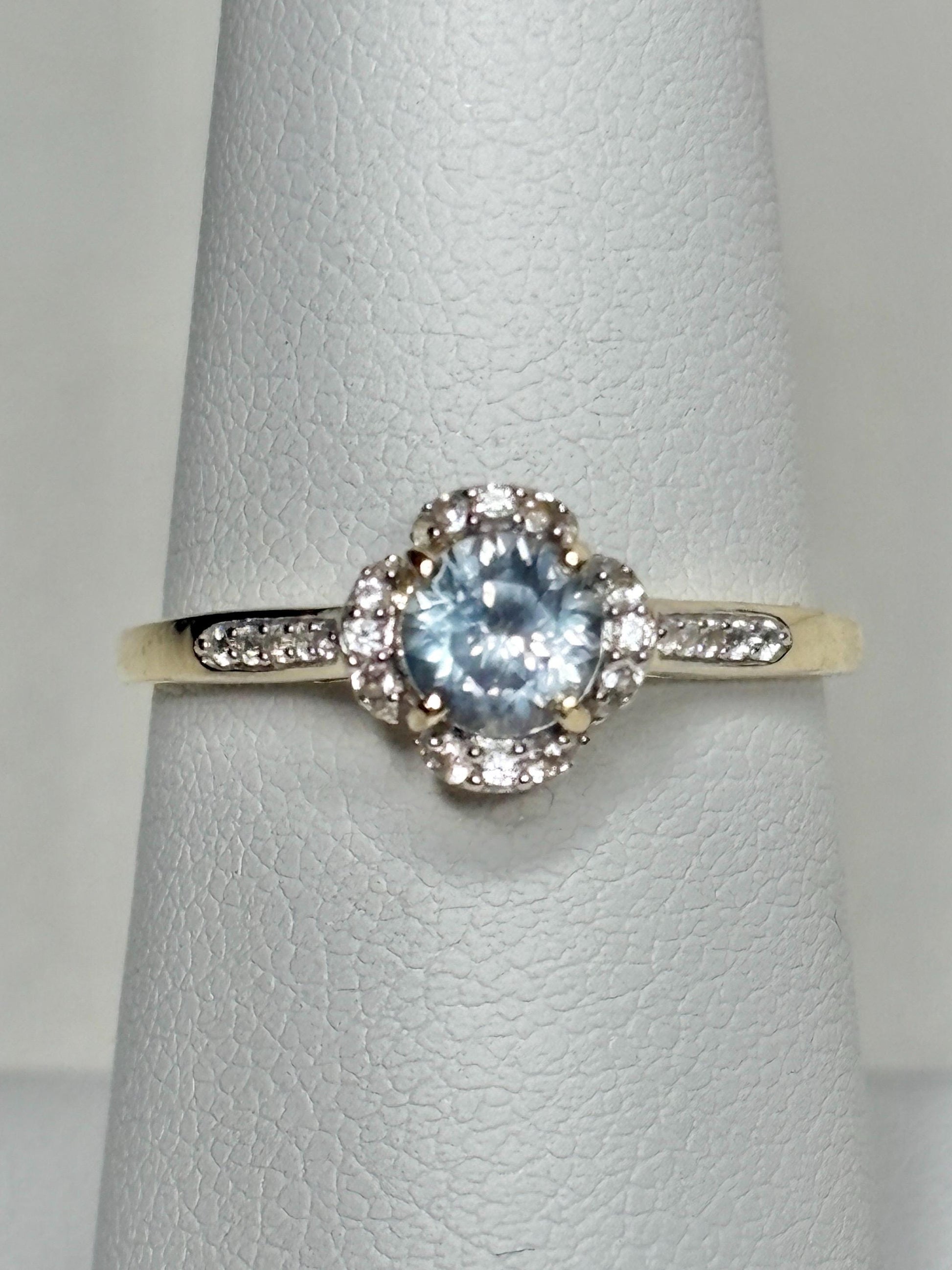 9k gold ring with a Montana sapphire and white zircon in a floral halo design.