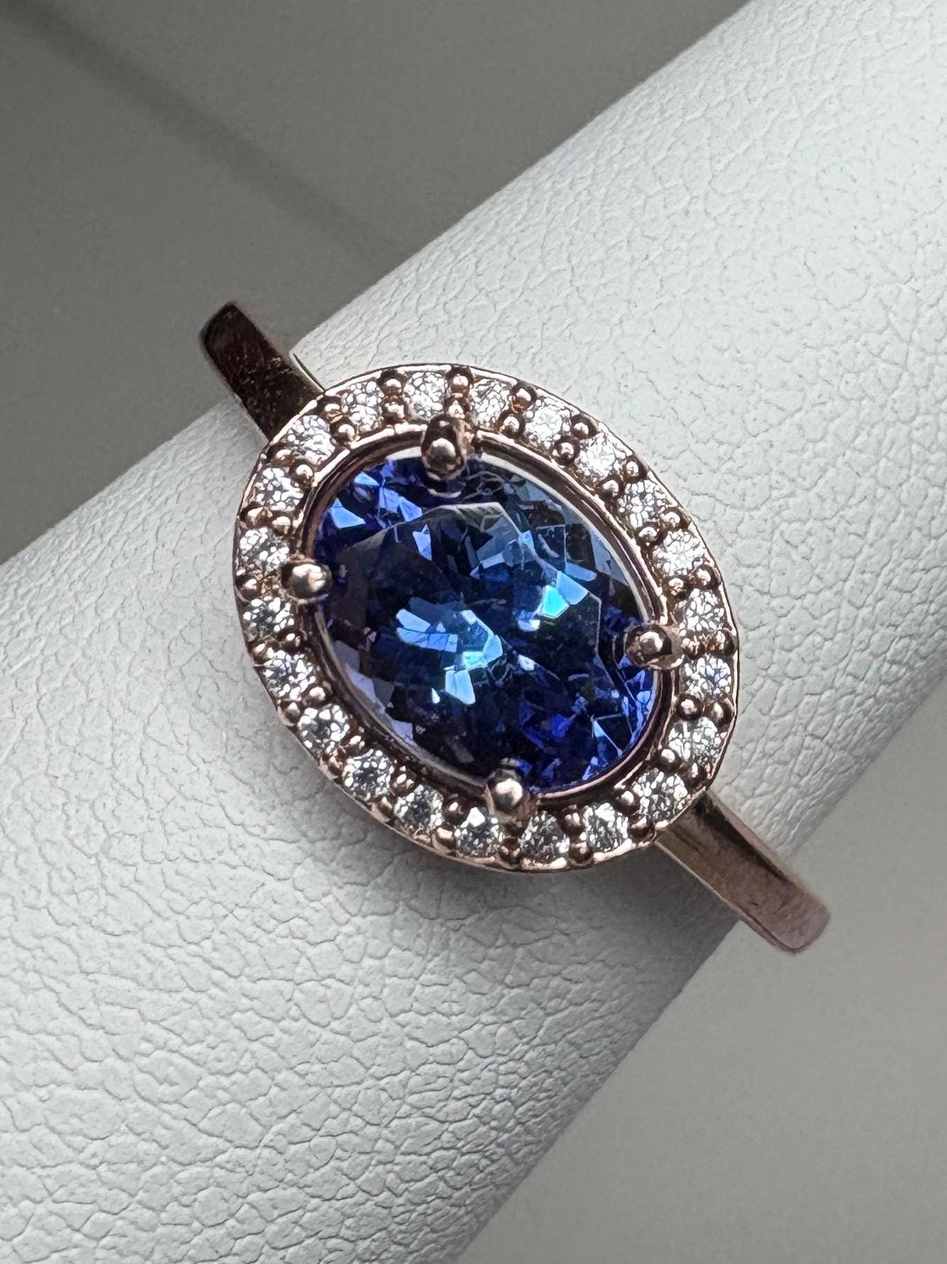 Oval tanzanite and diamond halo ring in rose gold.