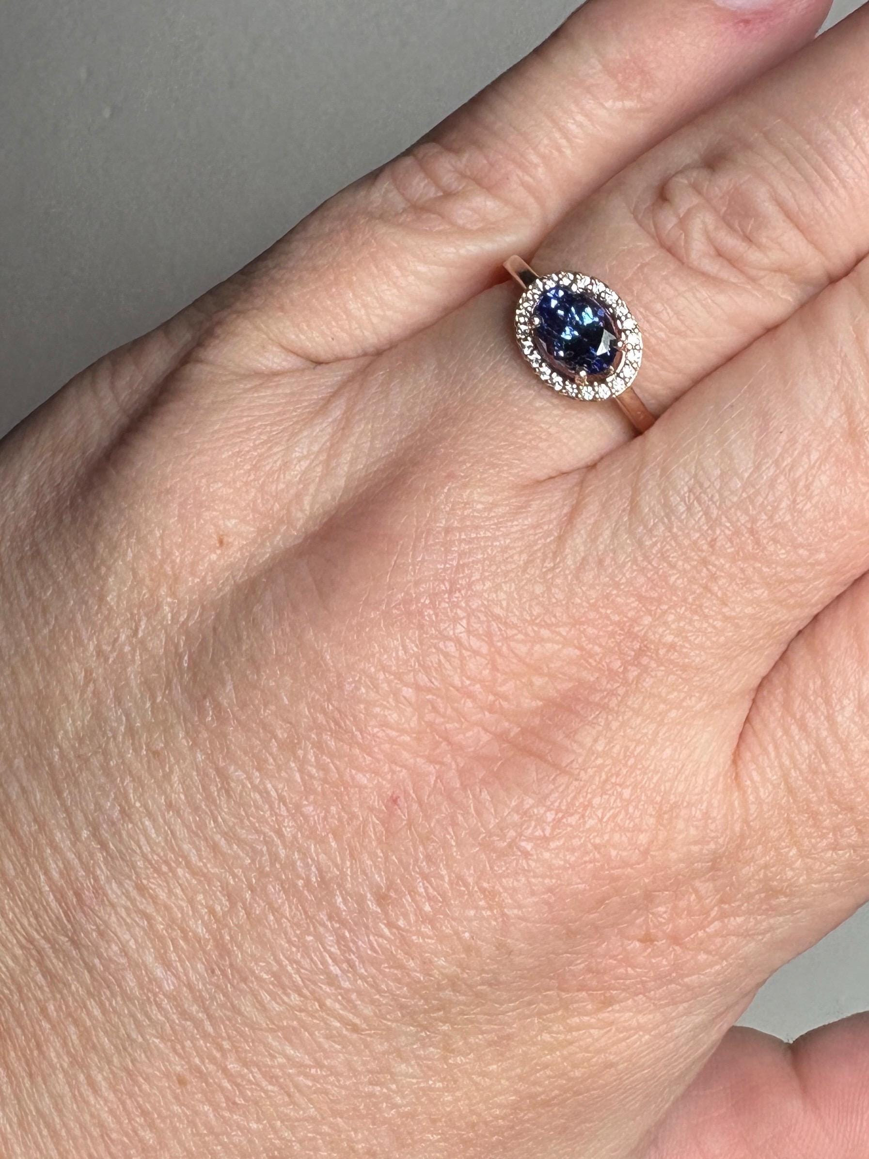 A rose gold ring with an oval tanzanite center stone surrounded by diamonds.