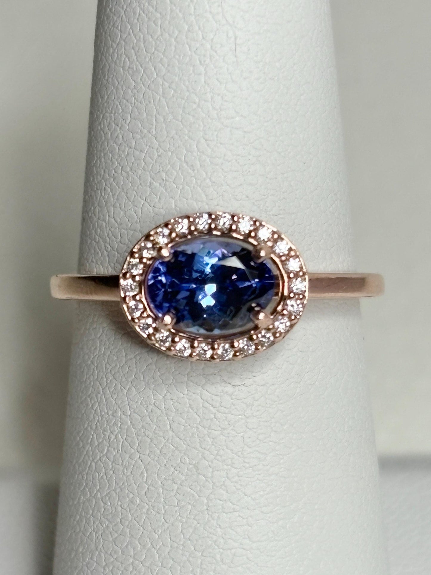 Oval tanzanite ring with diamond halo in 14k rose gold.