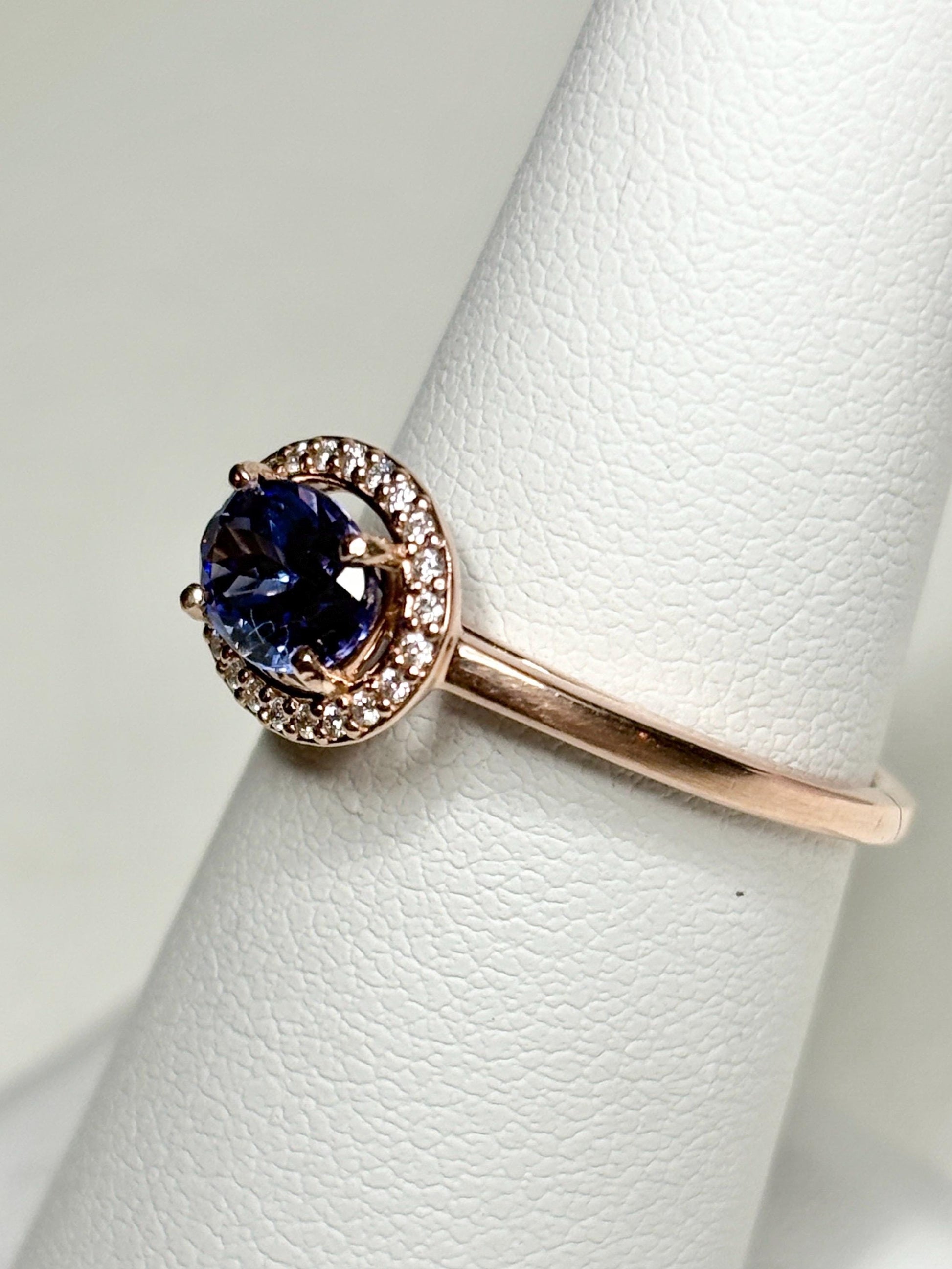 Rose gold ring with a tanzanite center stone surrounded by diamonds.