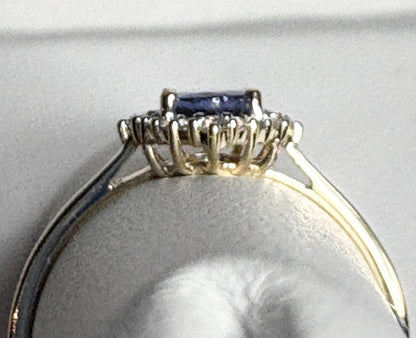 A 9k gold ring with an oval tanzanite center stone and a halo of white zircon.